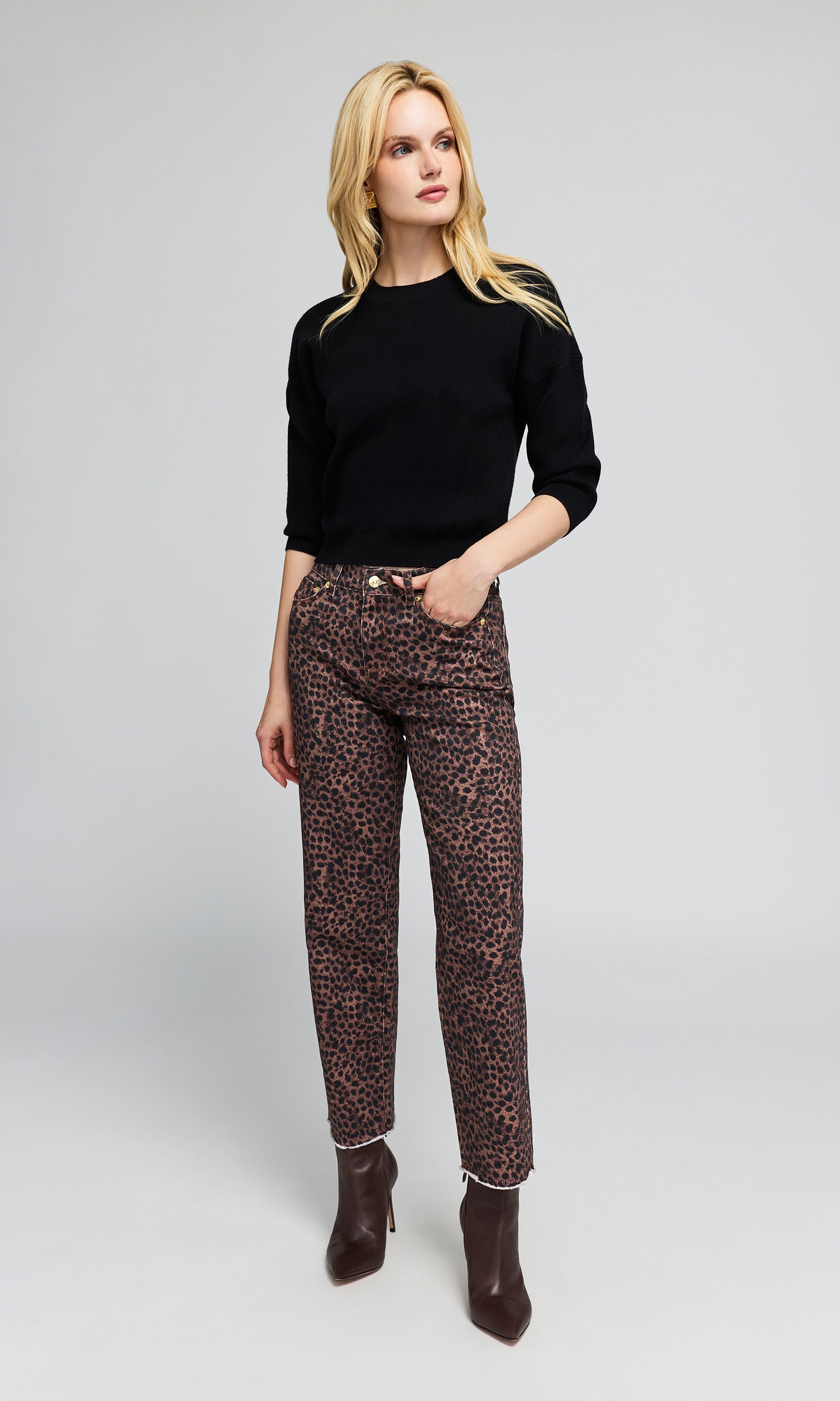 Model wearing leopard-print ankle-length jeans with a black long-sleeve top on a plain background.