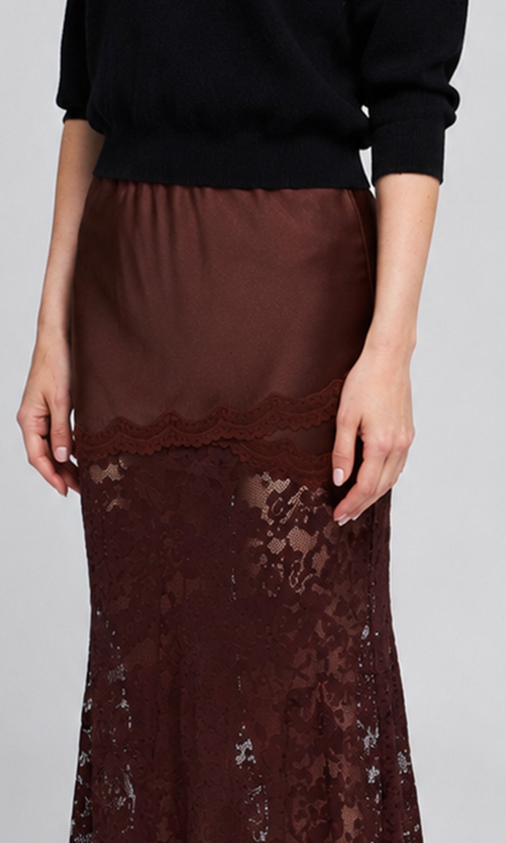 Close-up of a brown satin and lace combo skirt worn by a model with a black sweater.