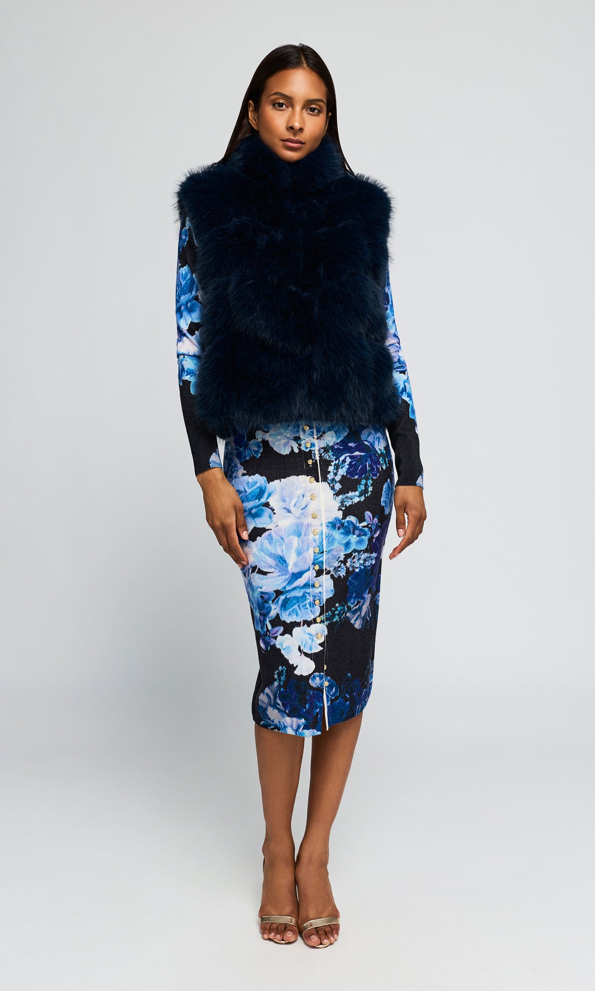 Model wearing a long-sleeve cardiga and skirt set with a blue and white floral print, paired with a dark navy faux-fur vest.