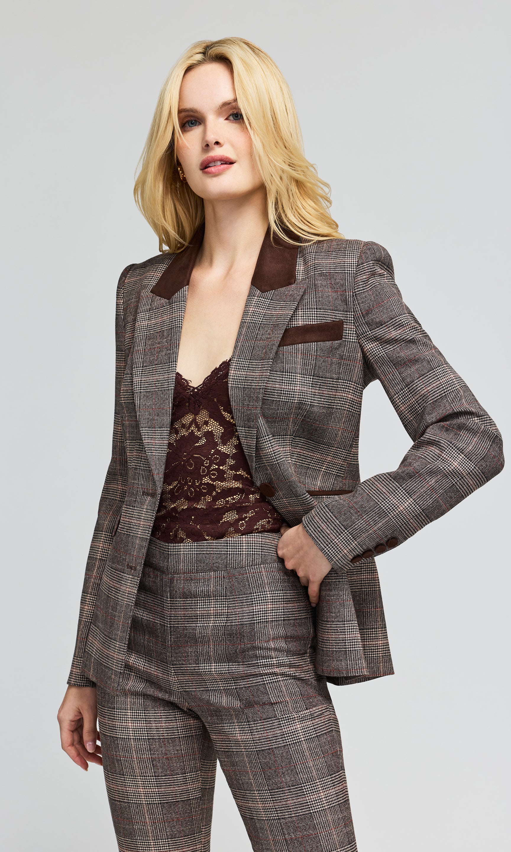 Side view of mdel wearing a brown and gray plaid blazer with dark brown lapels, styled over a brown lace camisole and matching plaid trousers.