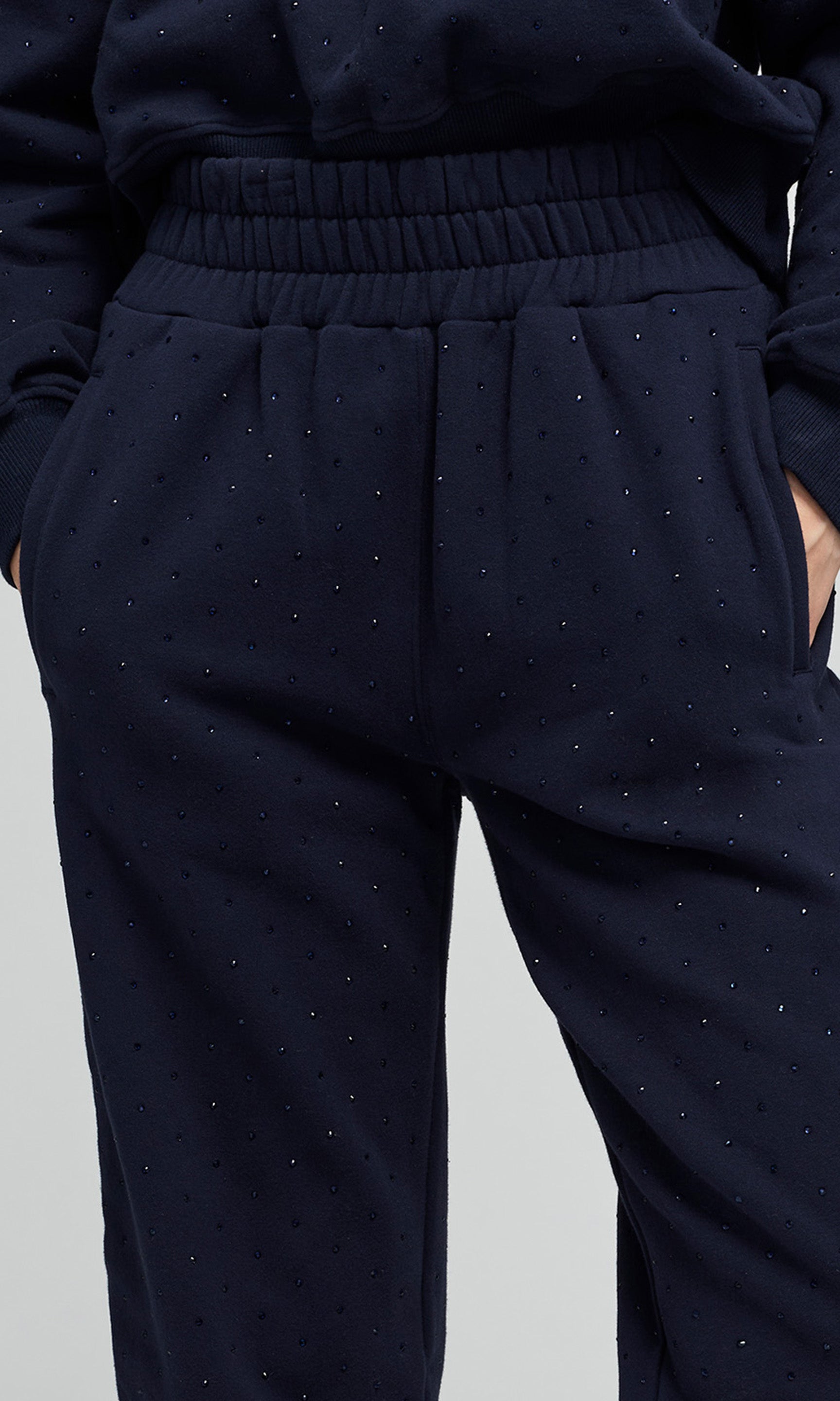 Close-up of navy blue jogger sweatpants with crystal embellishments and an elastic waistband.