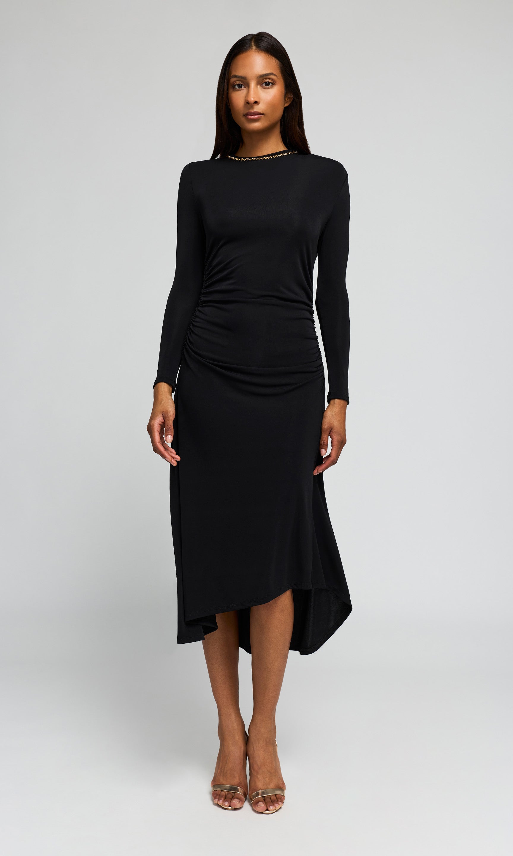 Model wearing a black long-sleeve midi dress with a gathered, ruched bodice on a background.