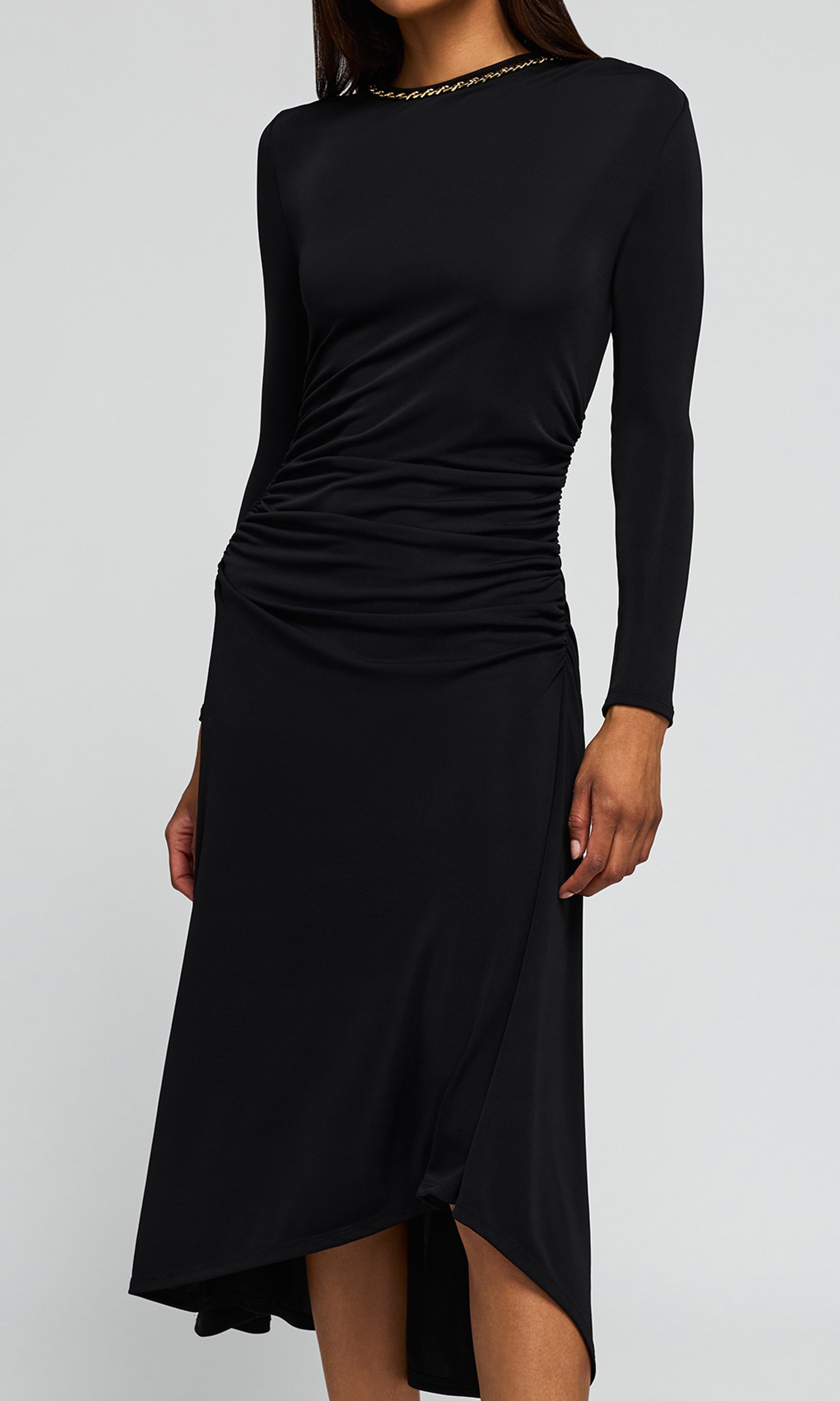 Close-up of a black long-sleeve midi dress with a gathered, ruched bodice on a background.
