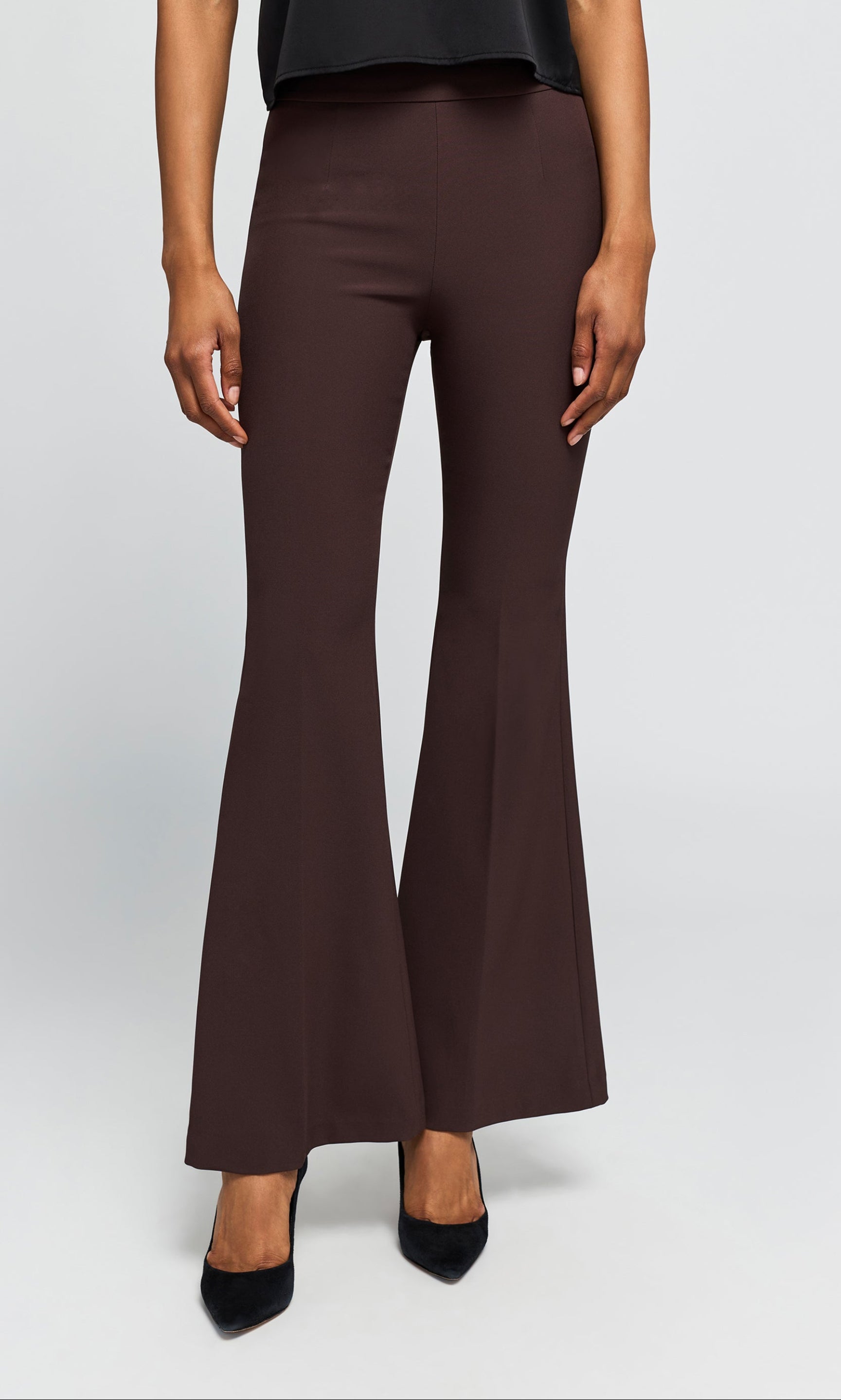 Model wearing brown crepe flared trousers with a black top on a plain background.