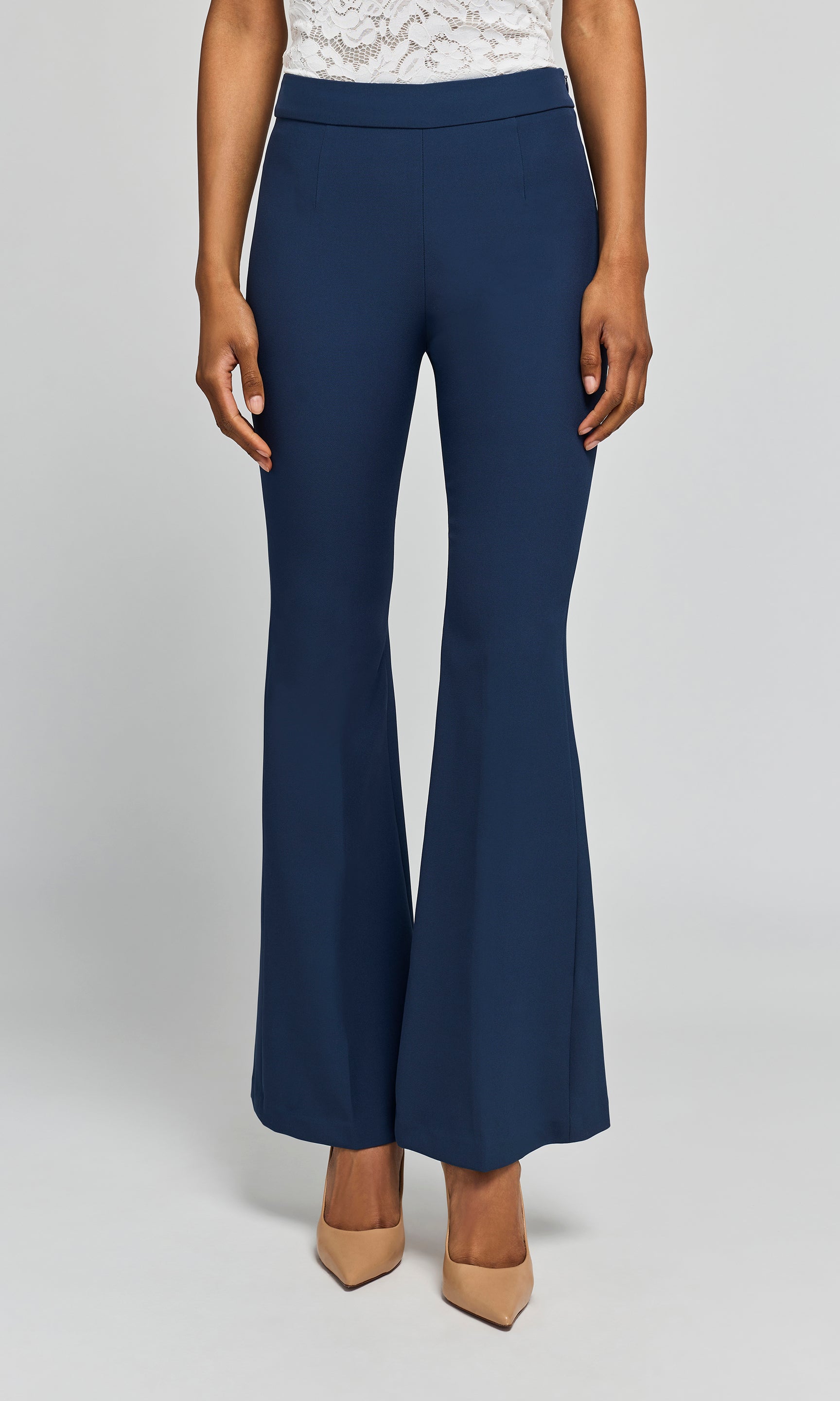 Model wearing navy crepe pants with a white top and beige heels on a plain background.