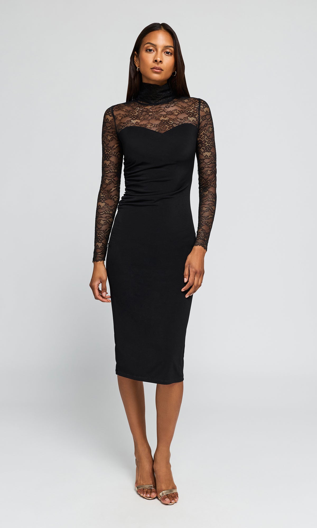 Model wearing a black midi dress with long sheer lace sleeves and a high lace neck, against a plain background.