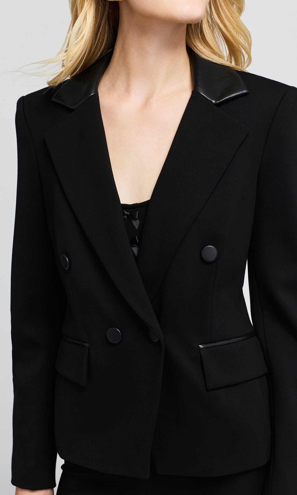Close-up of a black double-breasted blazer with contrasting black leather-like lapels.