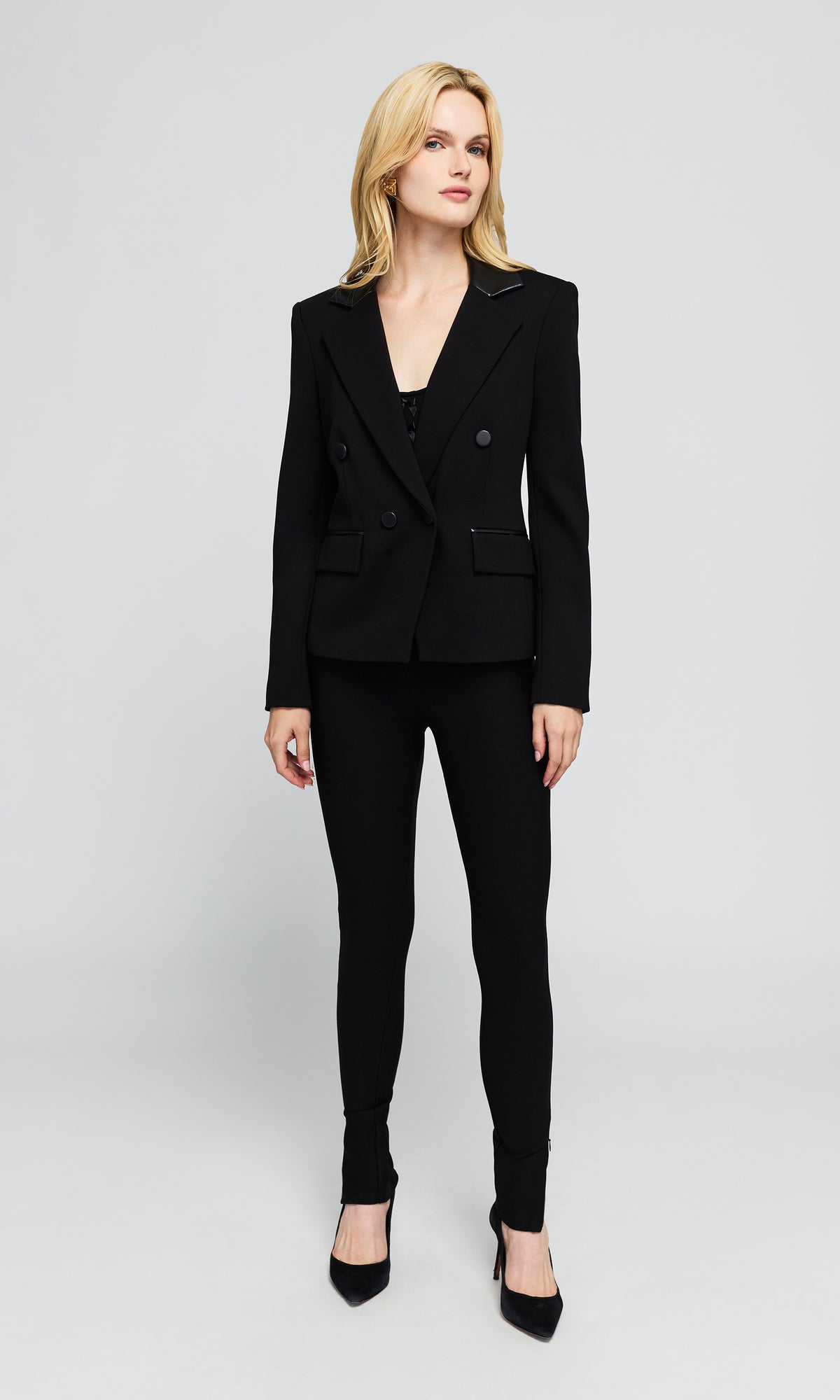 Model wearing a black double-breasted blazer, black slim-fit trousers, and black pointed-toe heels.