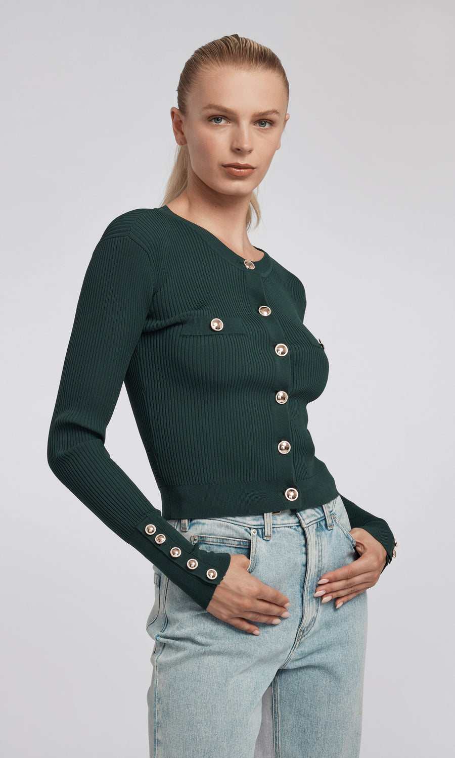 A cropped green rib cardigan adorned with gold buttons, highlighting a chic and fashionable look.