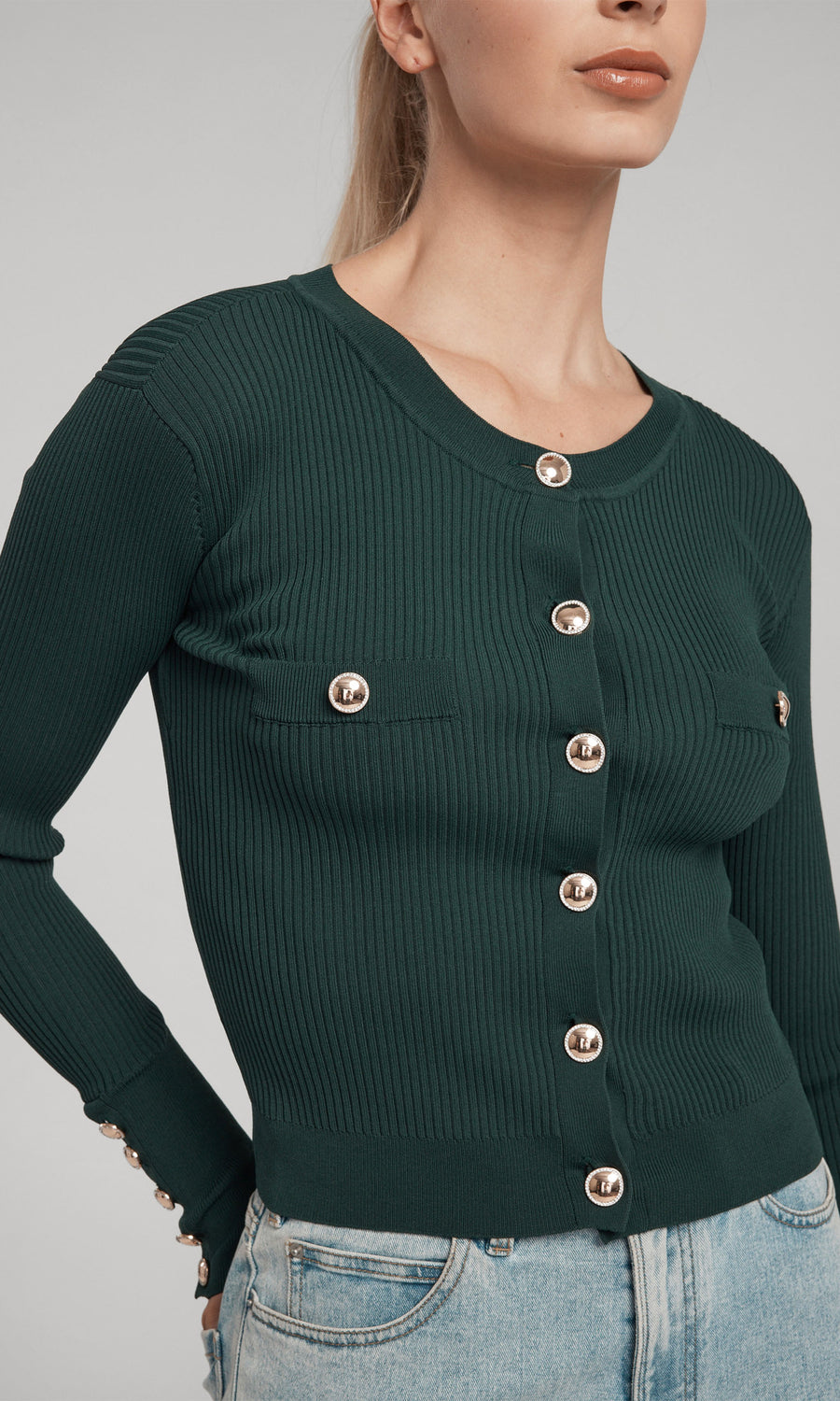 A cropped green rib cardigan adorned with gold buttons, highlighting a chic and fashionable look.