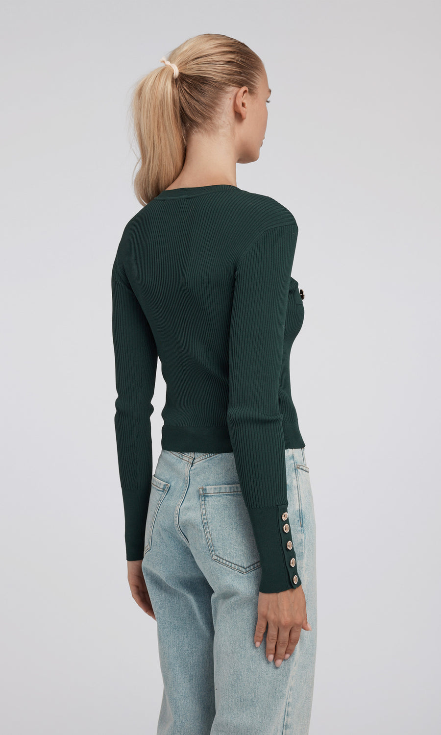 A cropped green rib cardigan adorned with gold buttons, highlighting a chic and fashionable look.