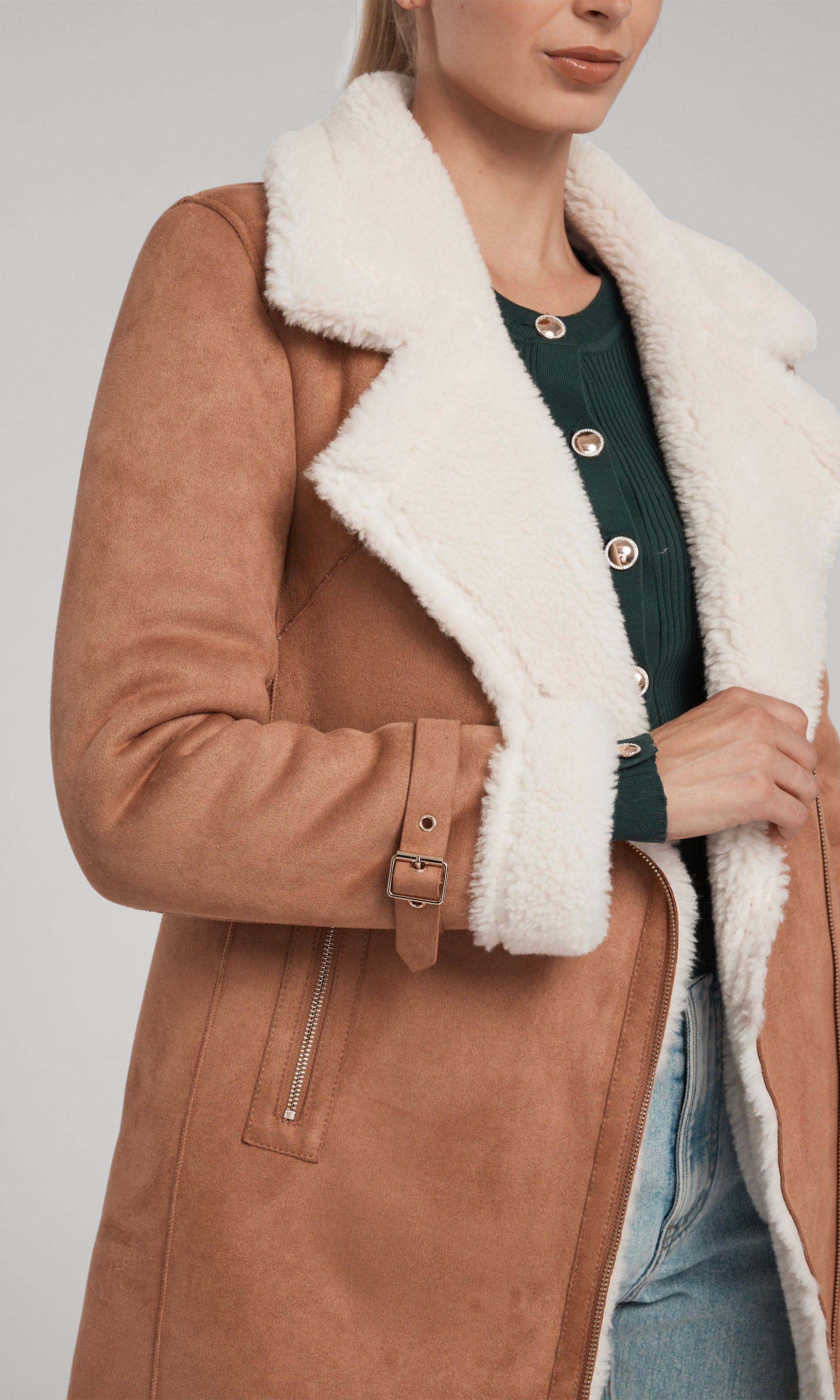 The image features a model in a chic brown coat made of suede, adorned with a soft faux fur shearling collar for added comfort.