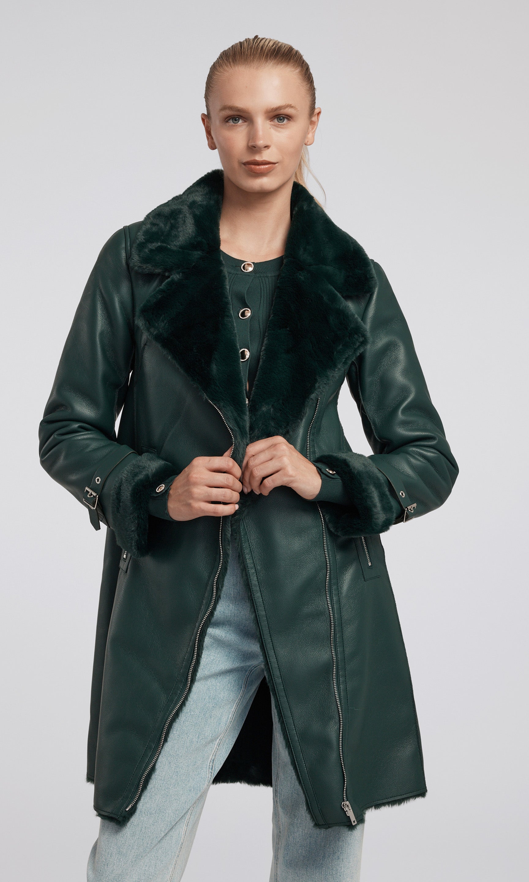 A model showcases a stylish green suede coat adorned with a luxurious faux fur collar, exuding elegance and sophistication.