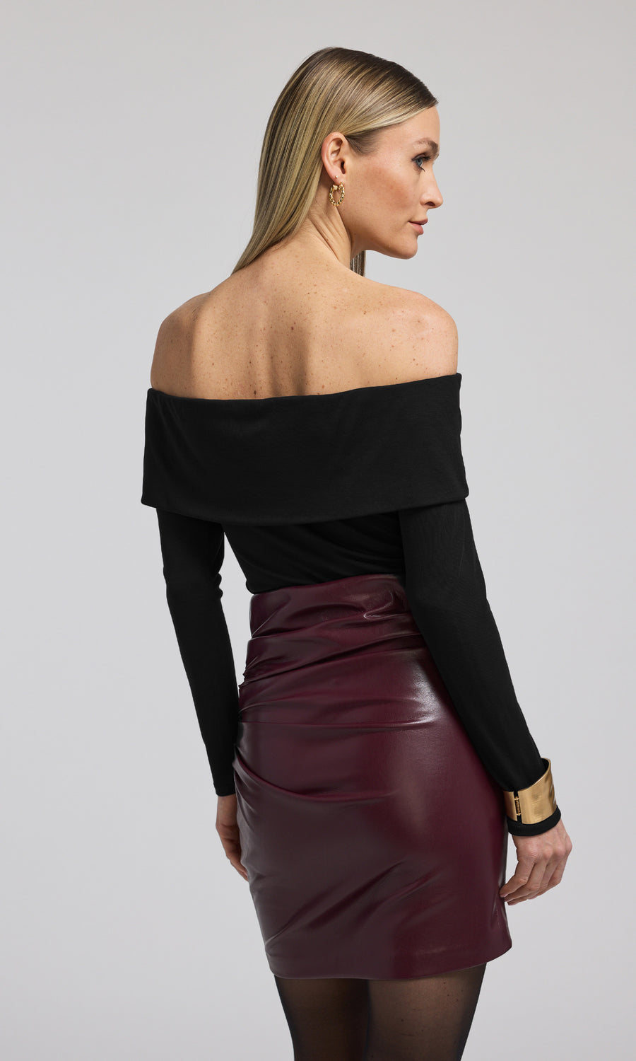 The model showcases a stylish black off-the-shoulder top, highlighting elegance and contemporary fashion trends.