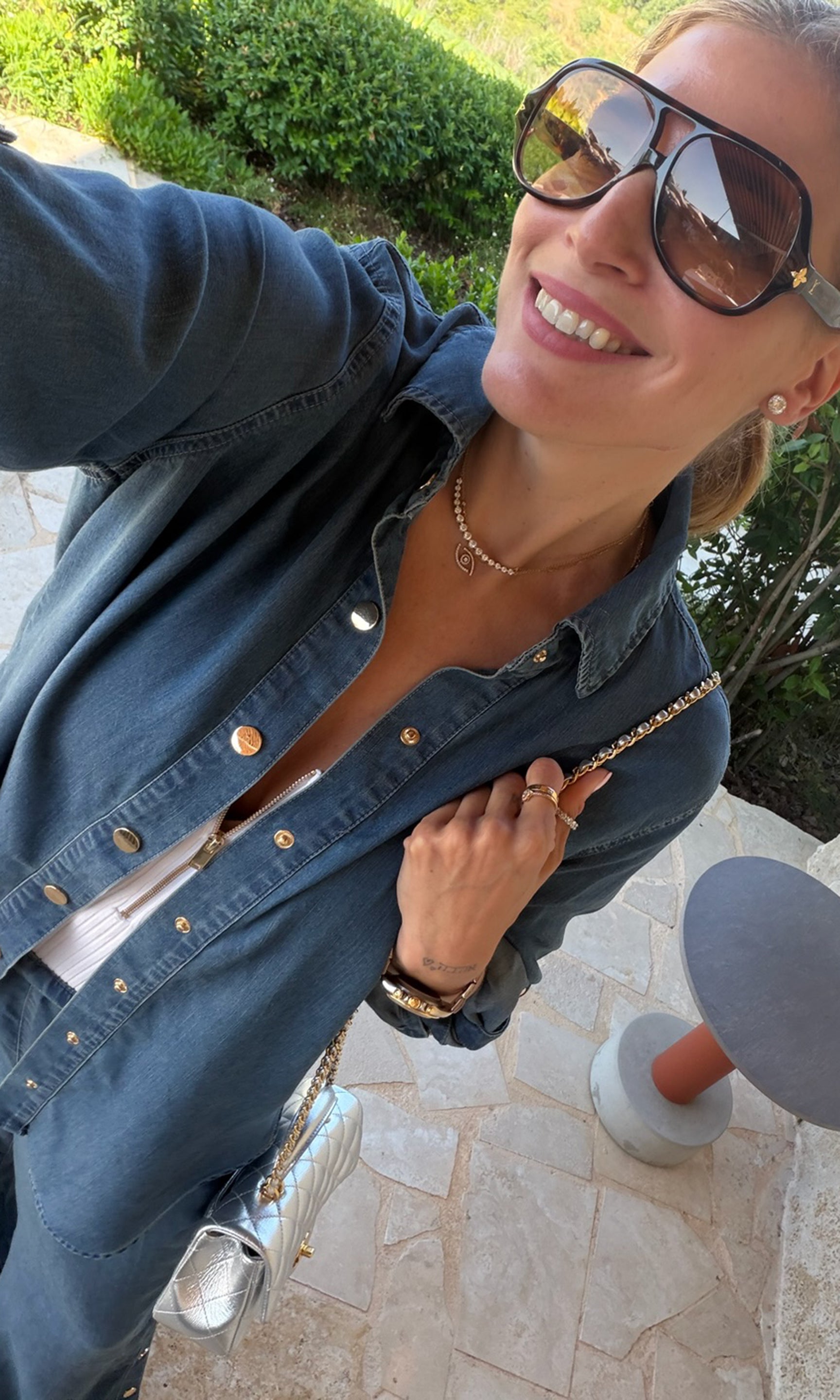 Founder Roni wearing a blue denim shirt with gold-tone buttons and a white top underneath.