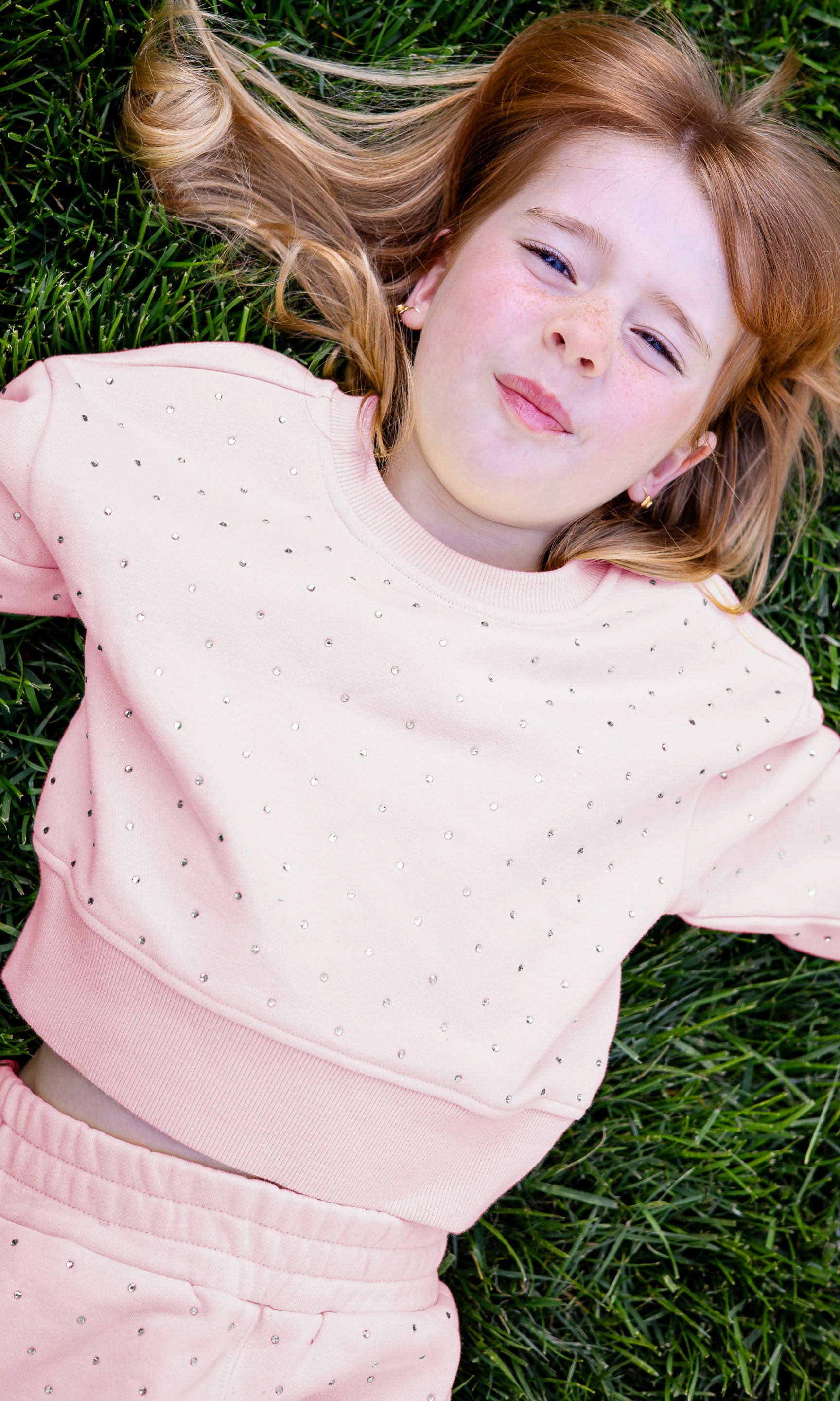 Young girl in a pink outfit lying on grass