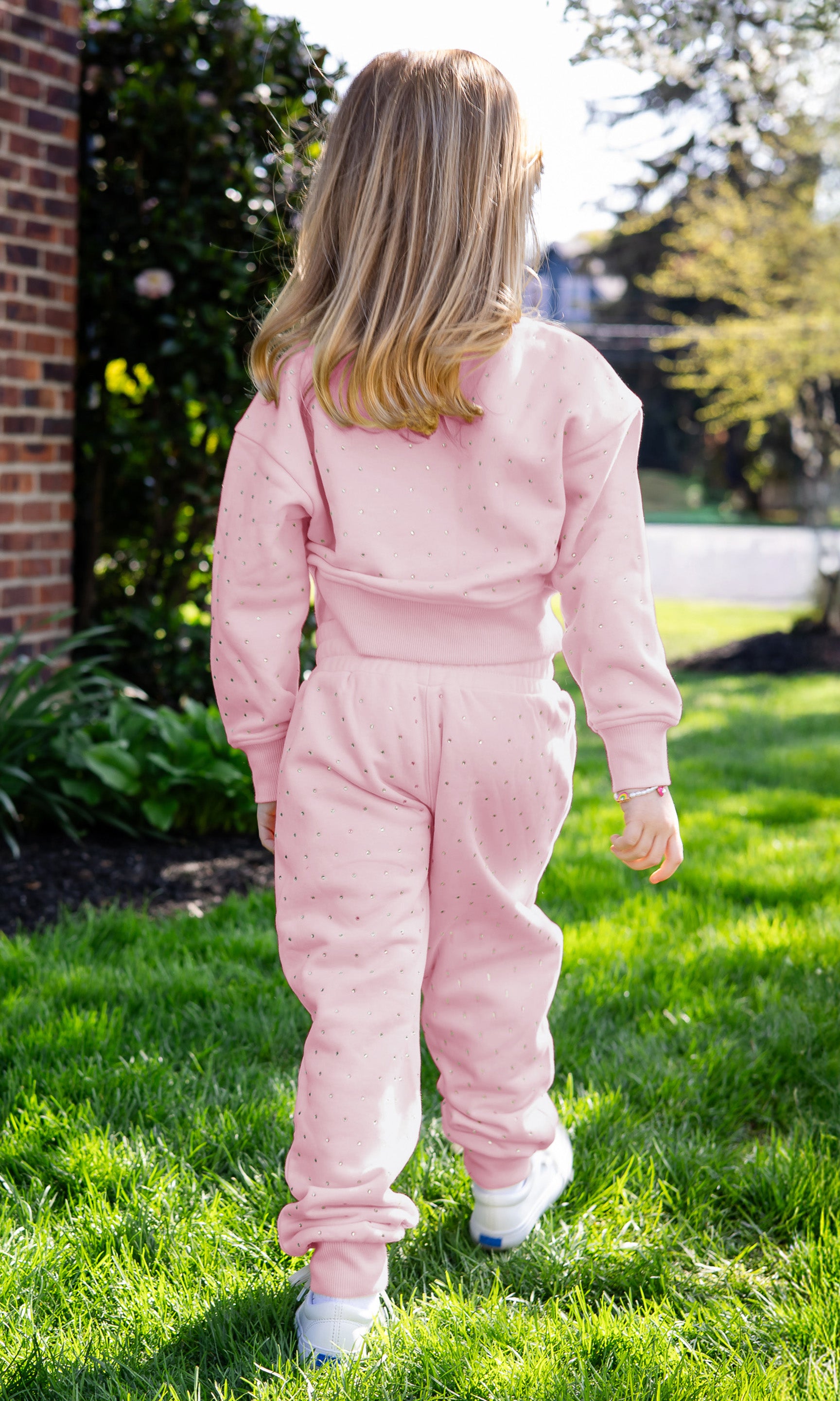 Child wearing a pink tracksuit walking on grass