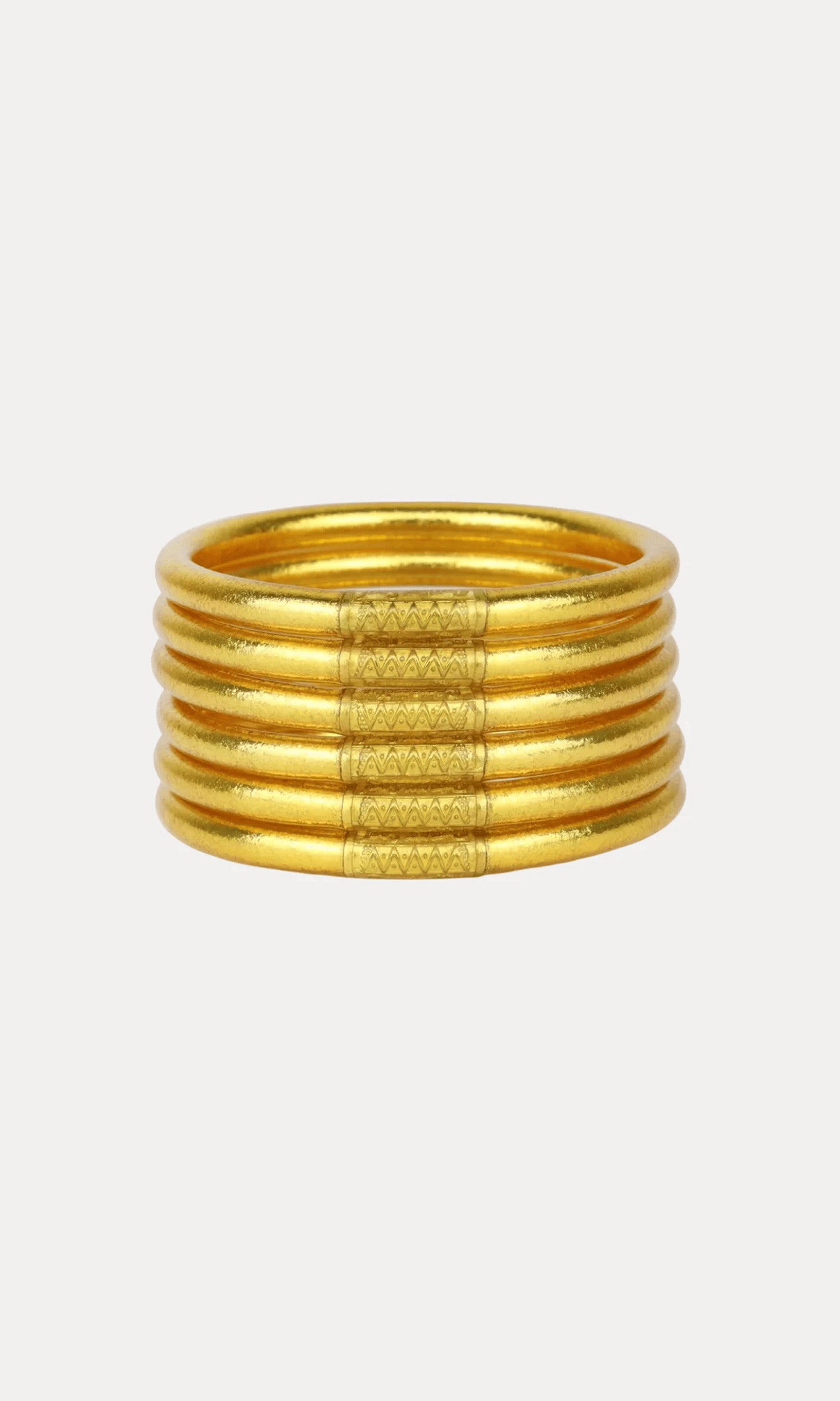 A gold-toned multi-band bracelet and textured central bands, shown on a plain light gray background.