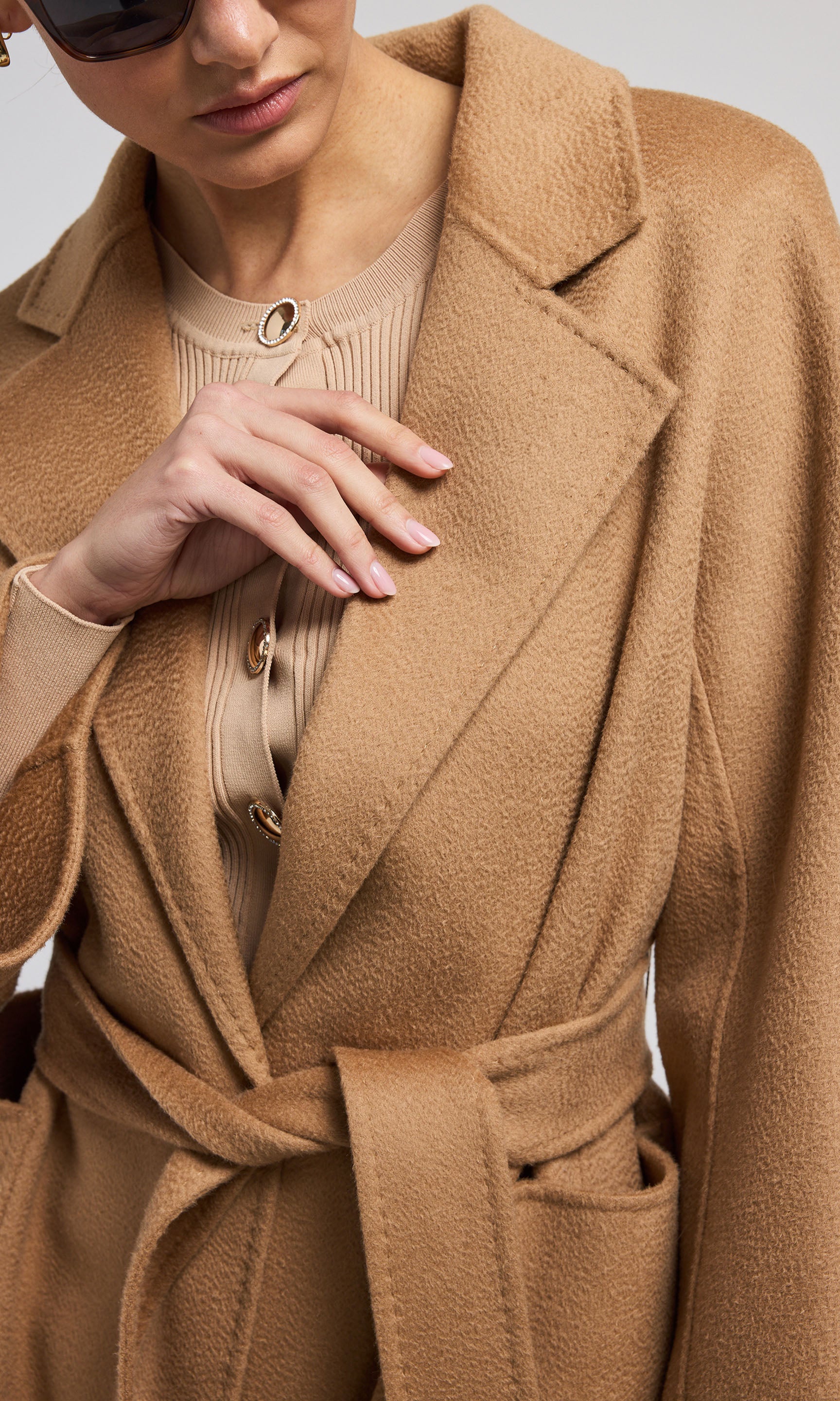  A chic camel wool coat with a belt, emphasizing elegance and warmth in its design for a fashionable look.