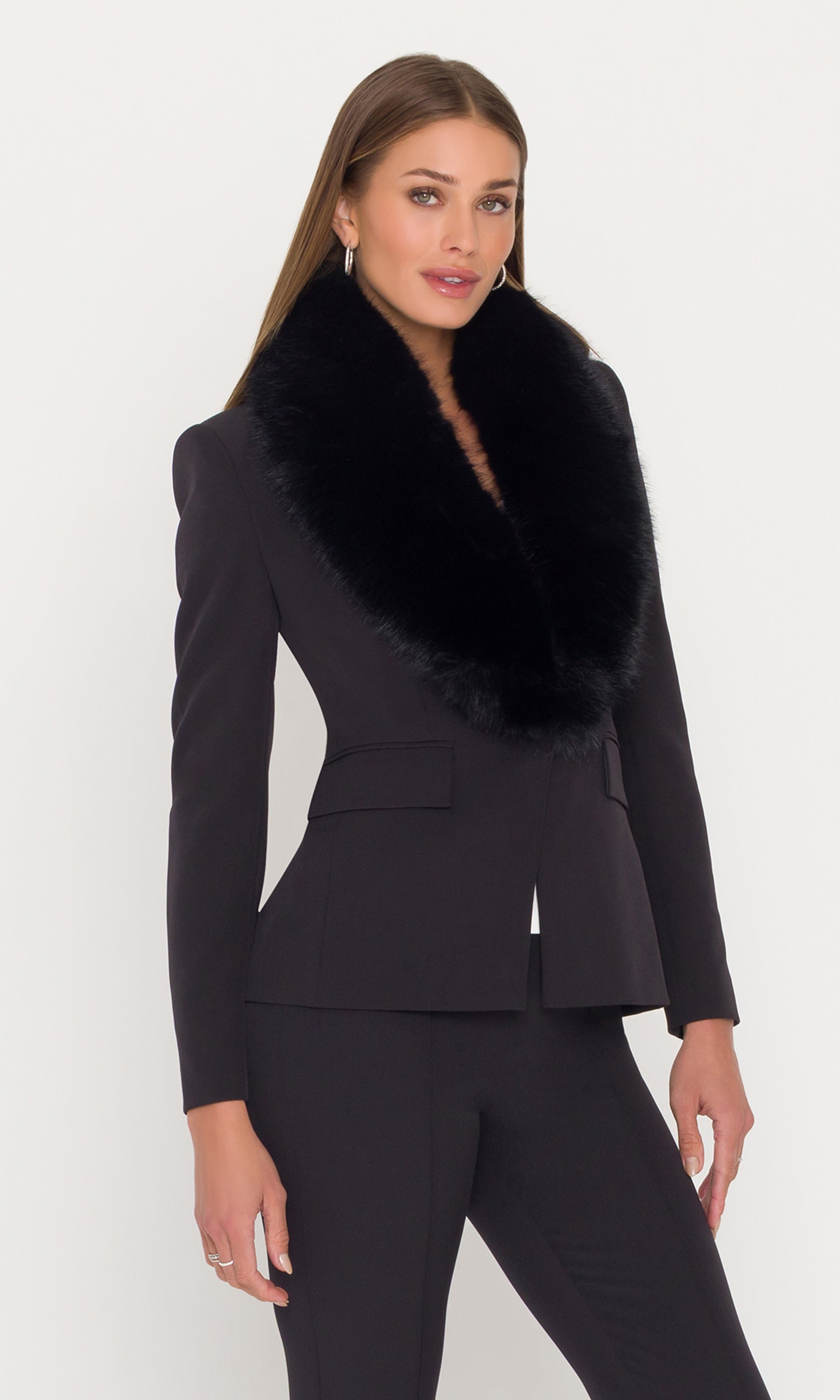 Side view of model wearing a black crepe blazer with a fur collar and black pants