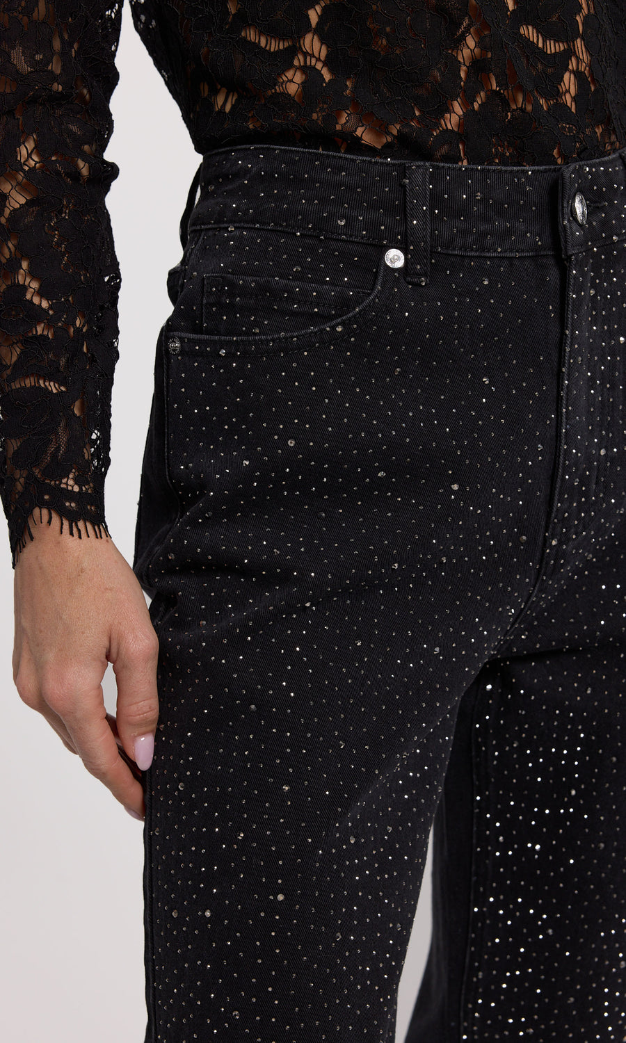 A close-up of black jeans featuring crystal embellishments, showcasing a stylish and elegant design.