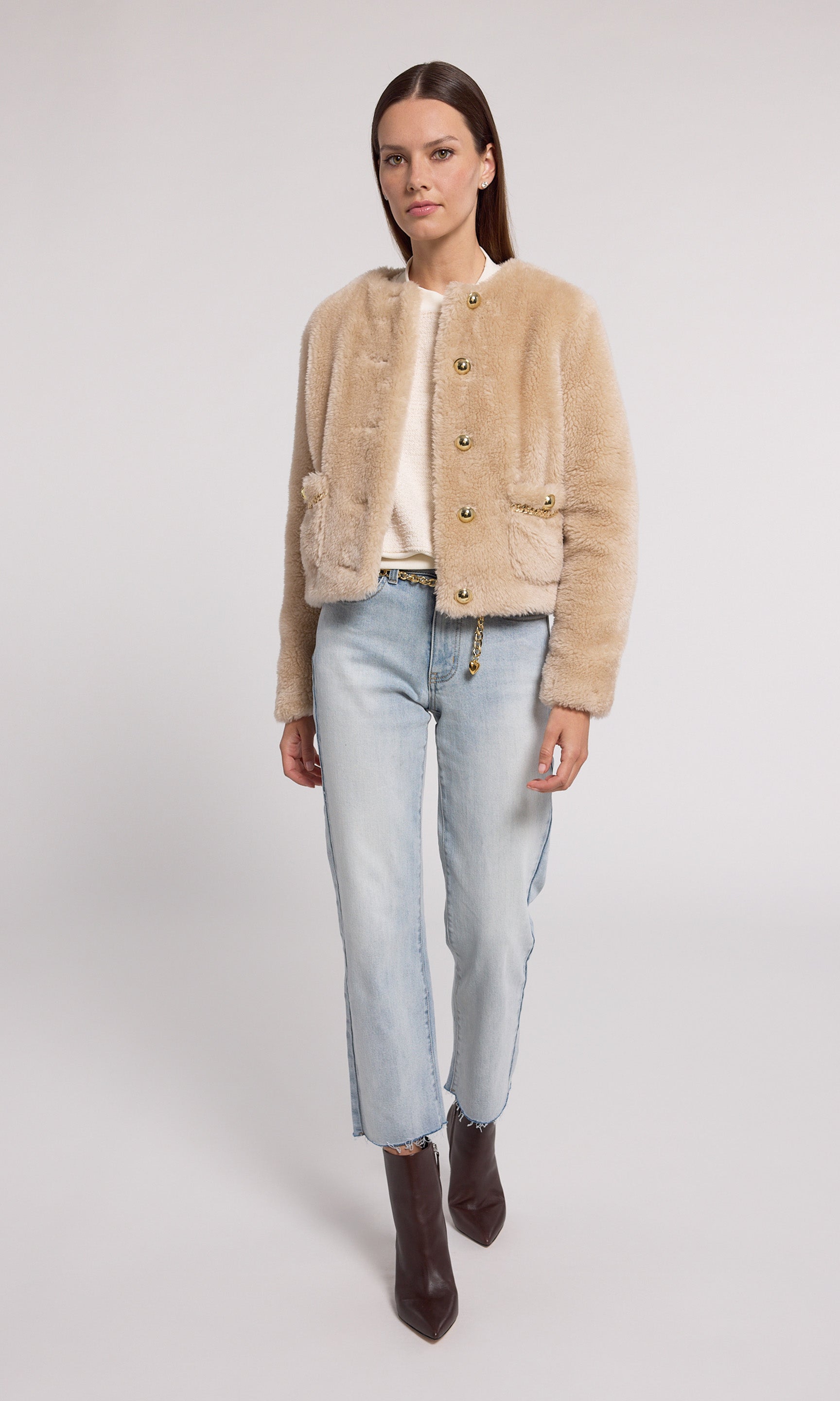 The image features a model in a chic beige faux fur jacket, highlighted by gold buttons and a stylish gold chain.