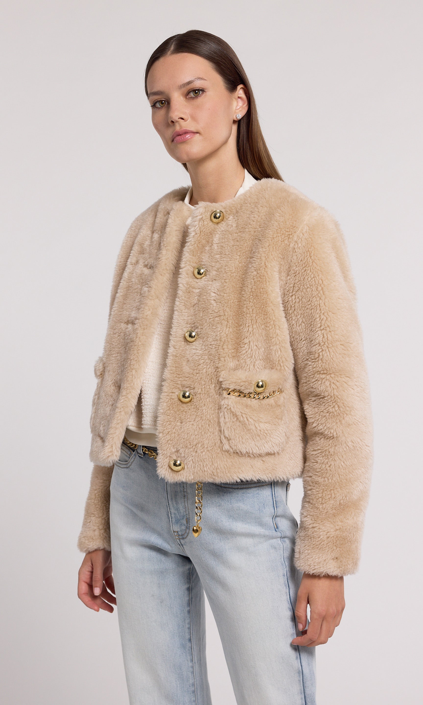 The image features a model in a chic beige faux fur jacket, highlighted by gold buttons and a stylish gold chain.