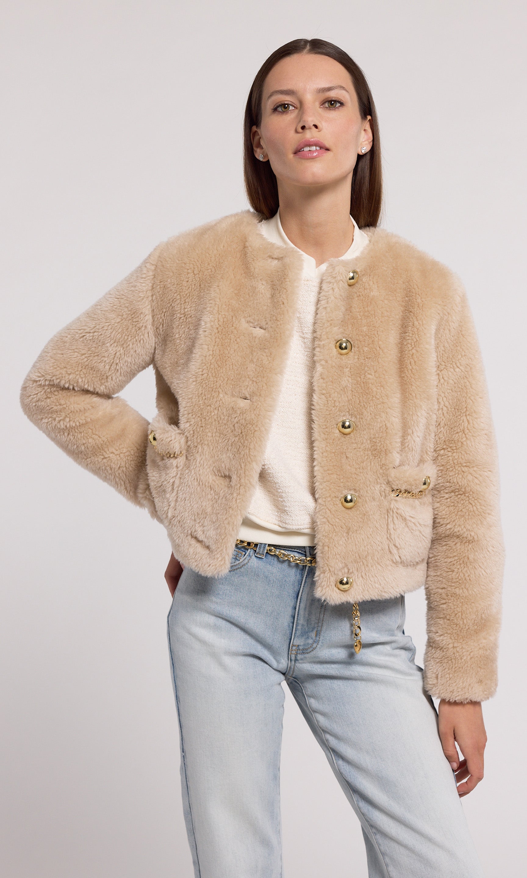 The image features a model in a chic beige faux fur jacket, highlighted by gold buttons and a stylish gold chain.