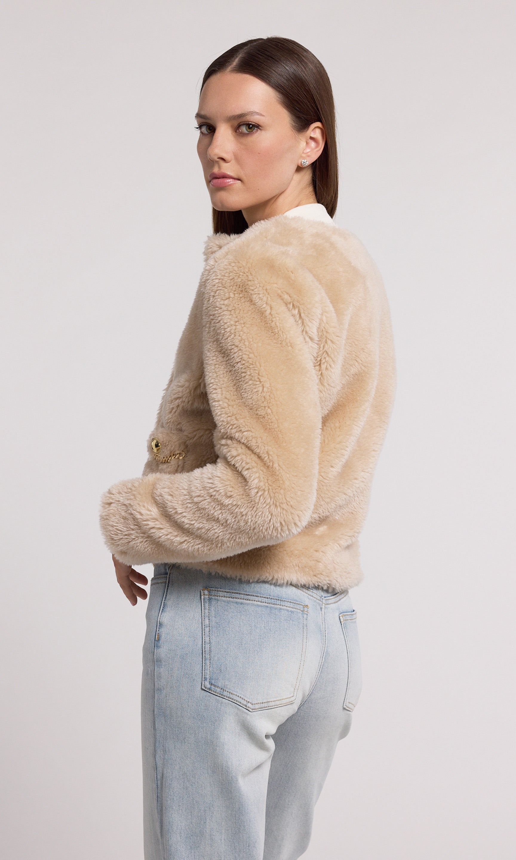 The image features a model in a chic beige faux fur jacket, highlighted by gold buttons and a stylish gold chain.