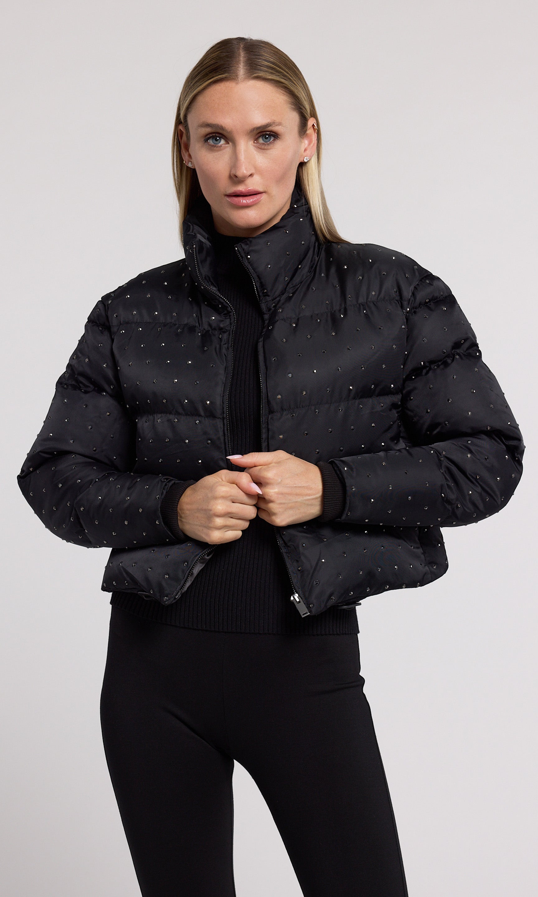 A stylish black cropped puffer adorned with crystal, showcasing a modern and playful design.