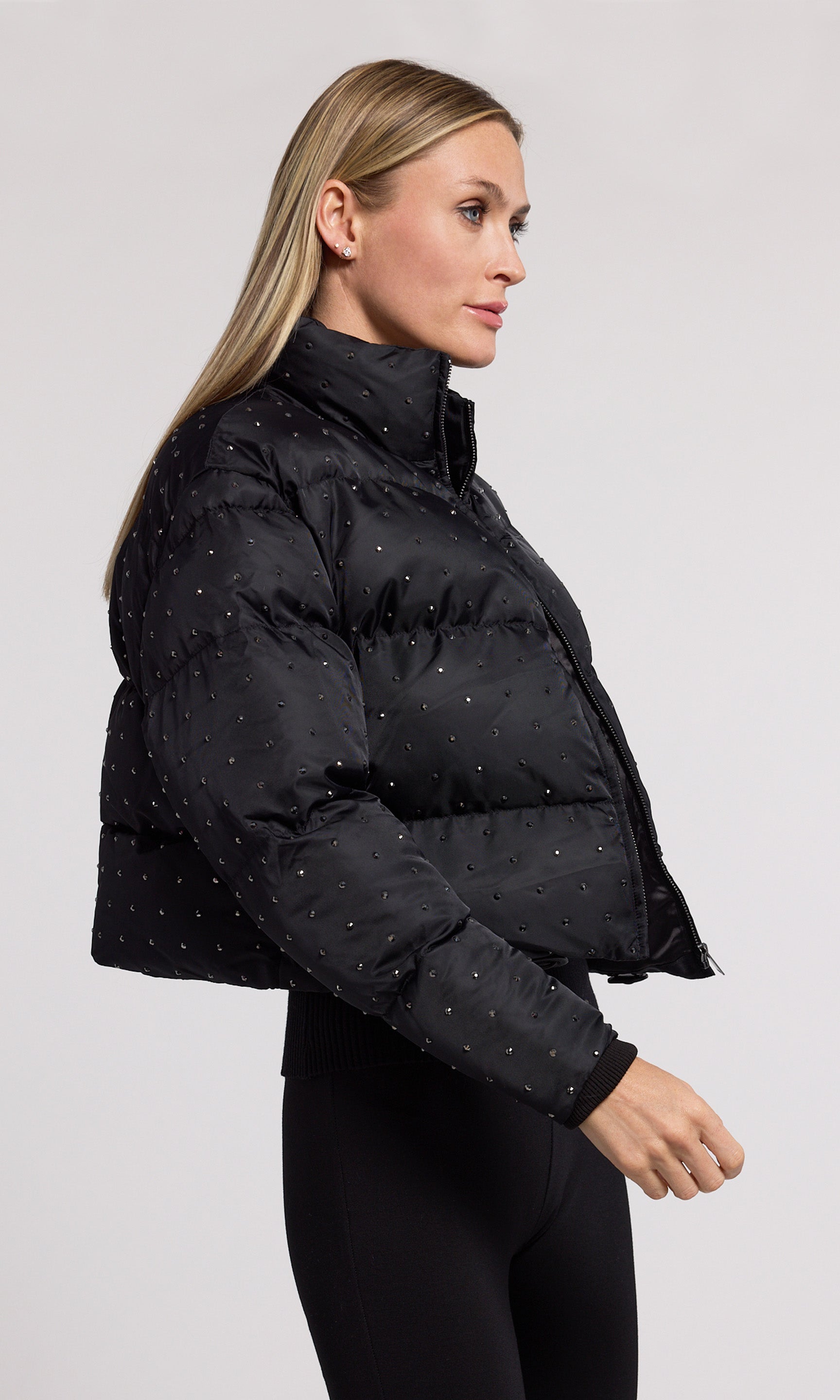 A stylish black cropped puffer adorned with crystal, showcasing a modern and playful design.