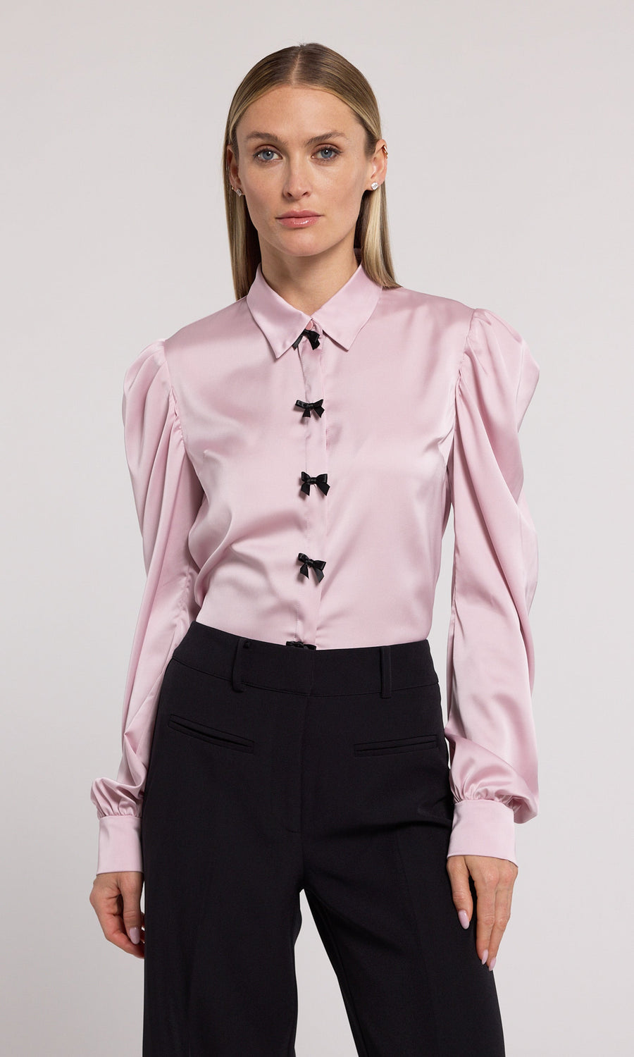 A pink blouse featuring elegant black bow detailing, showcasing a sophisticated and stylish design.