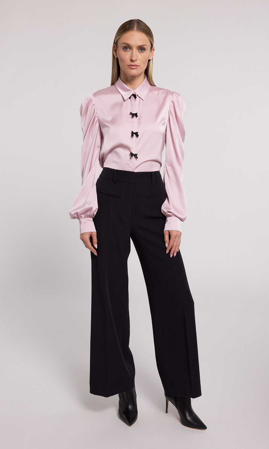 A pink blouse featuring elegant black bow detailing, showcasing a sophisticated and stylish design.