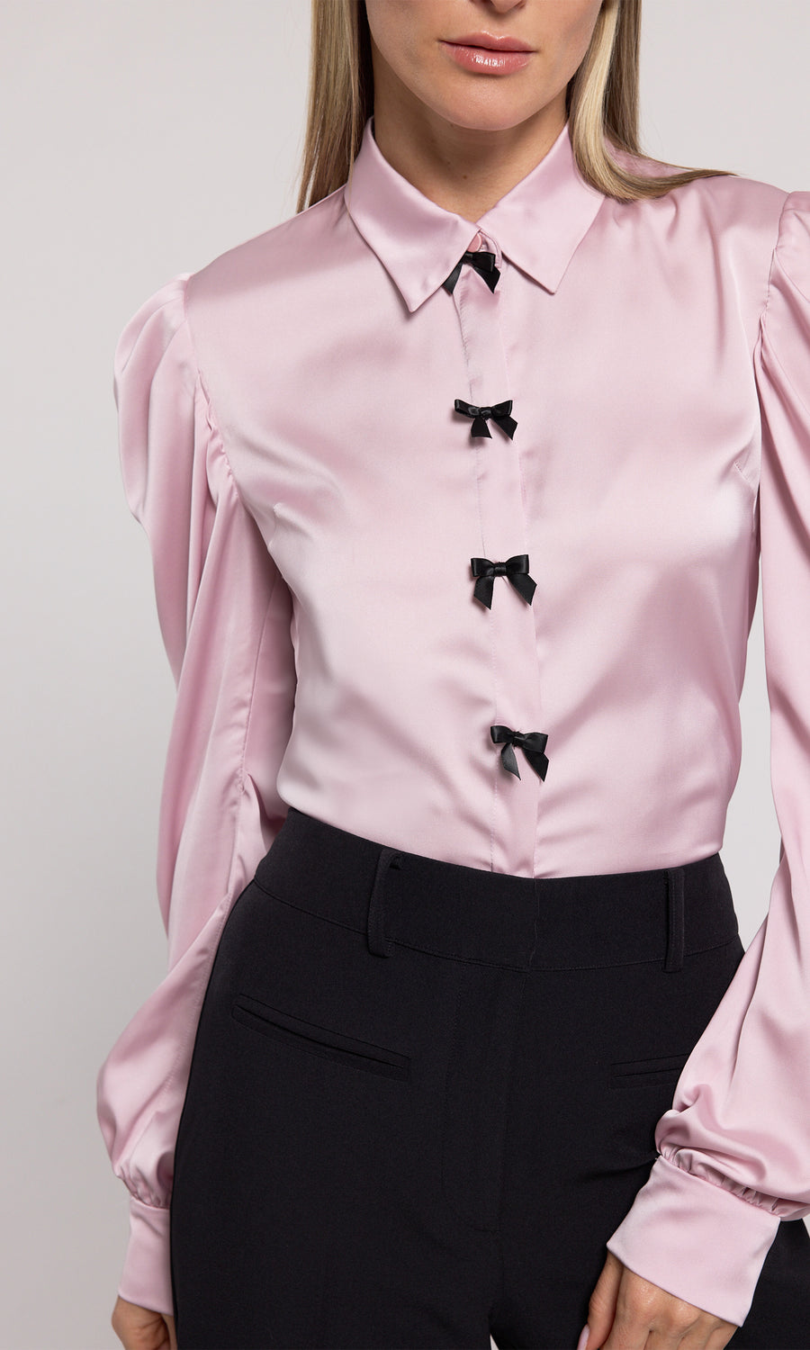 A pink blouse featuring elegant black bow detailing, showcasing a sophisticated and stylish design.