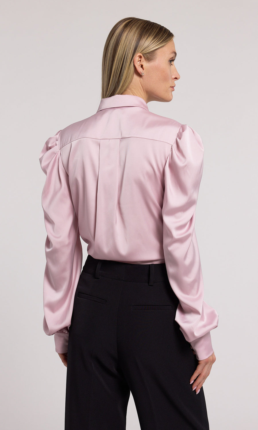 A pink blouse featuring elegant black bow detailing, showcasing a sophisticated and stylish design.