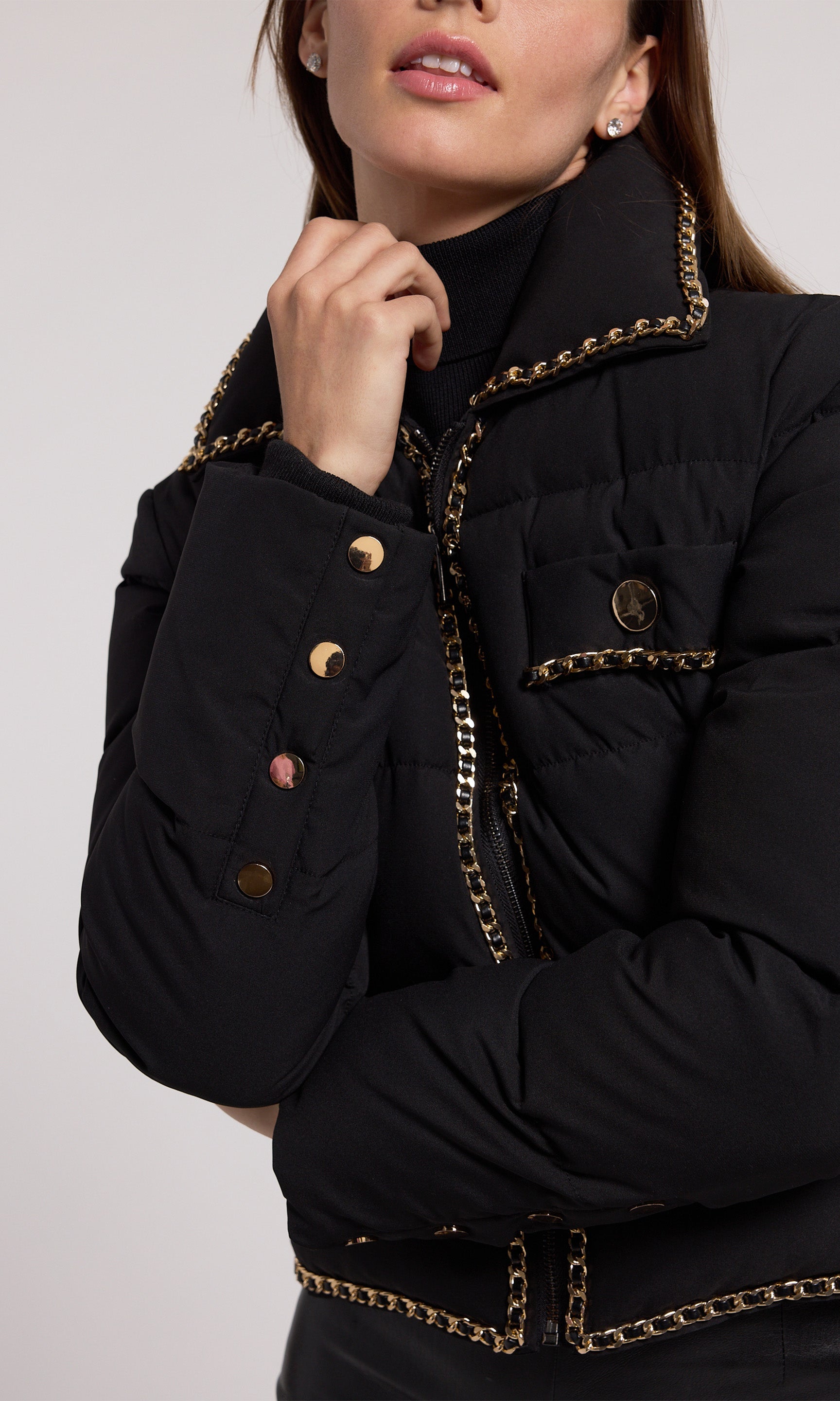 A stylish black puffer jacket featuring elegant gold detailing, perfect for a chic and modern look.