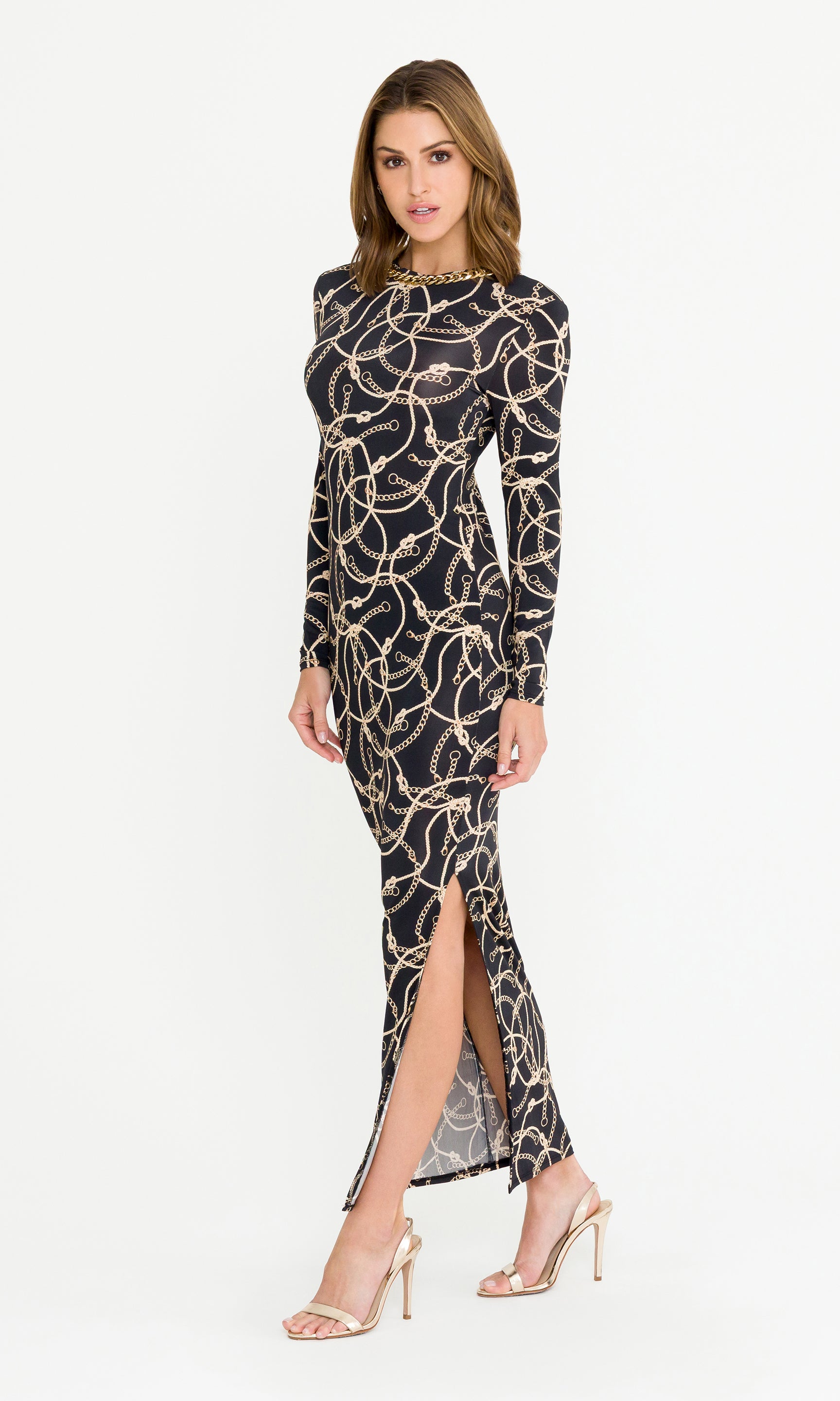 Woman wearing a black and gold patterned dress with a slit on a white background