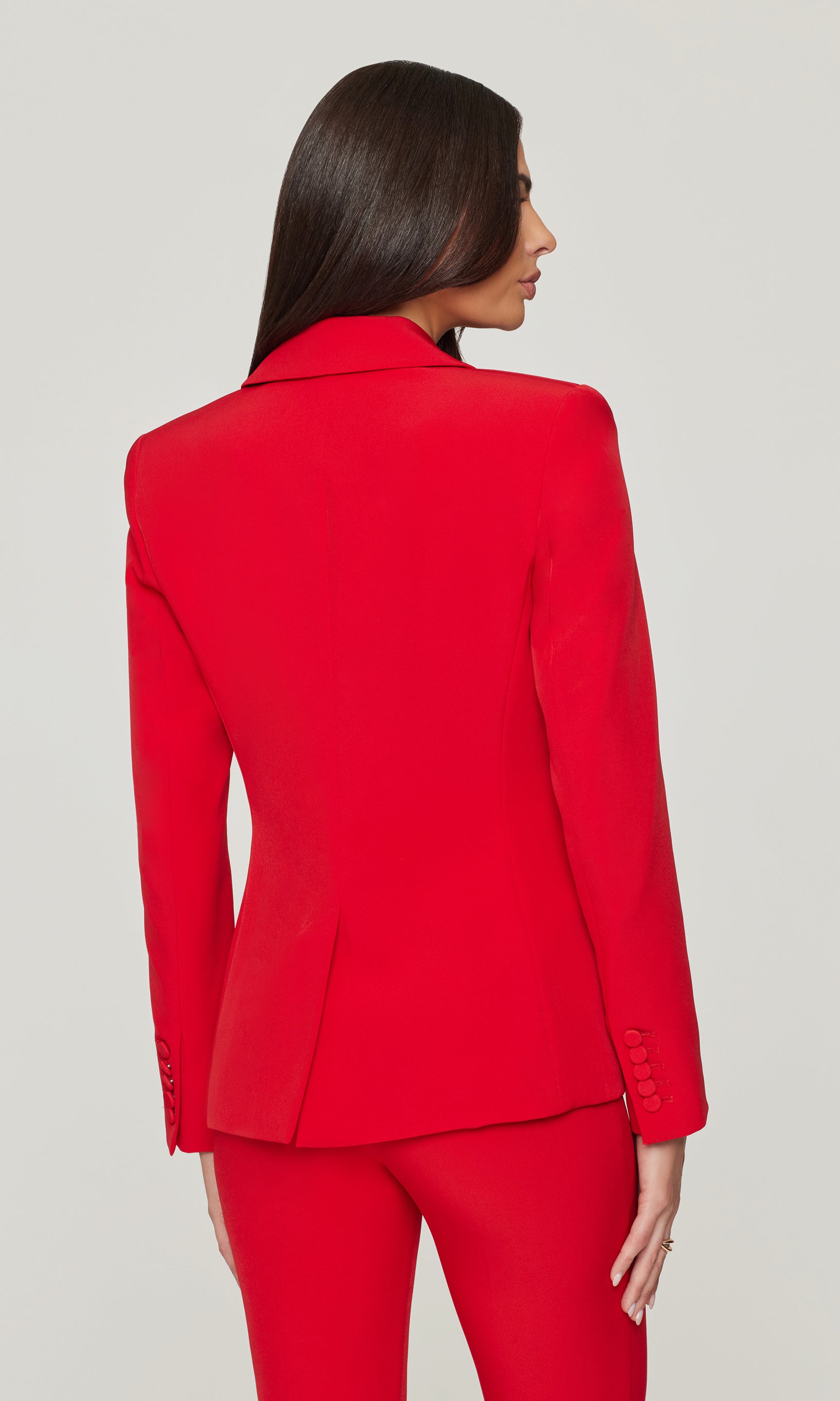 Back view of red suit jacket and pants on a plain background