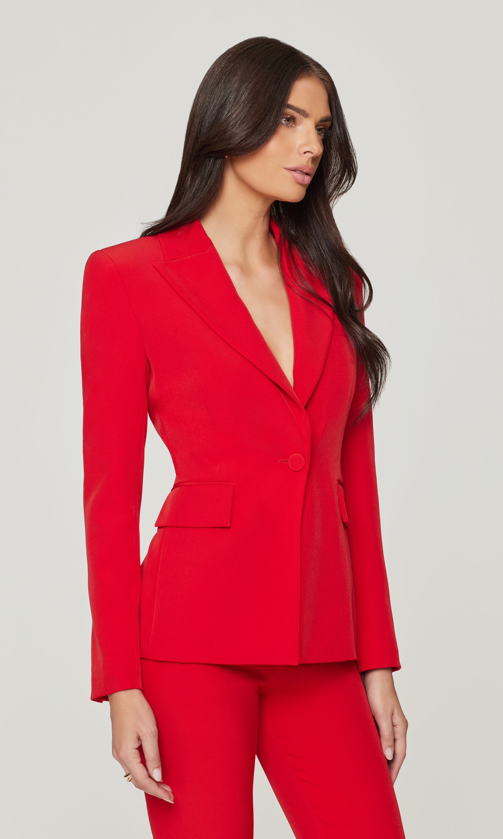 Side view of woman wearing a red suit on a plain background