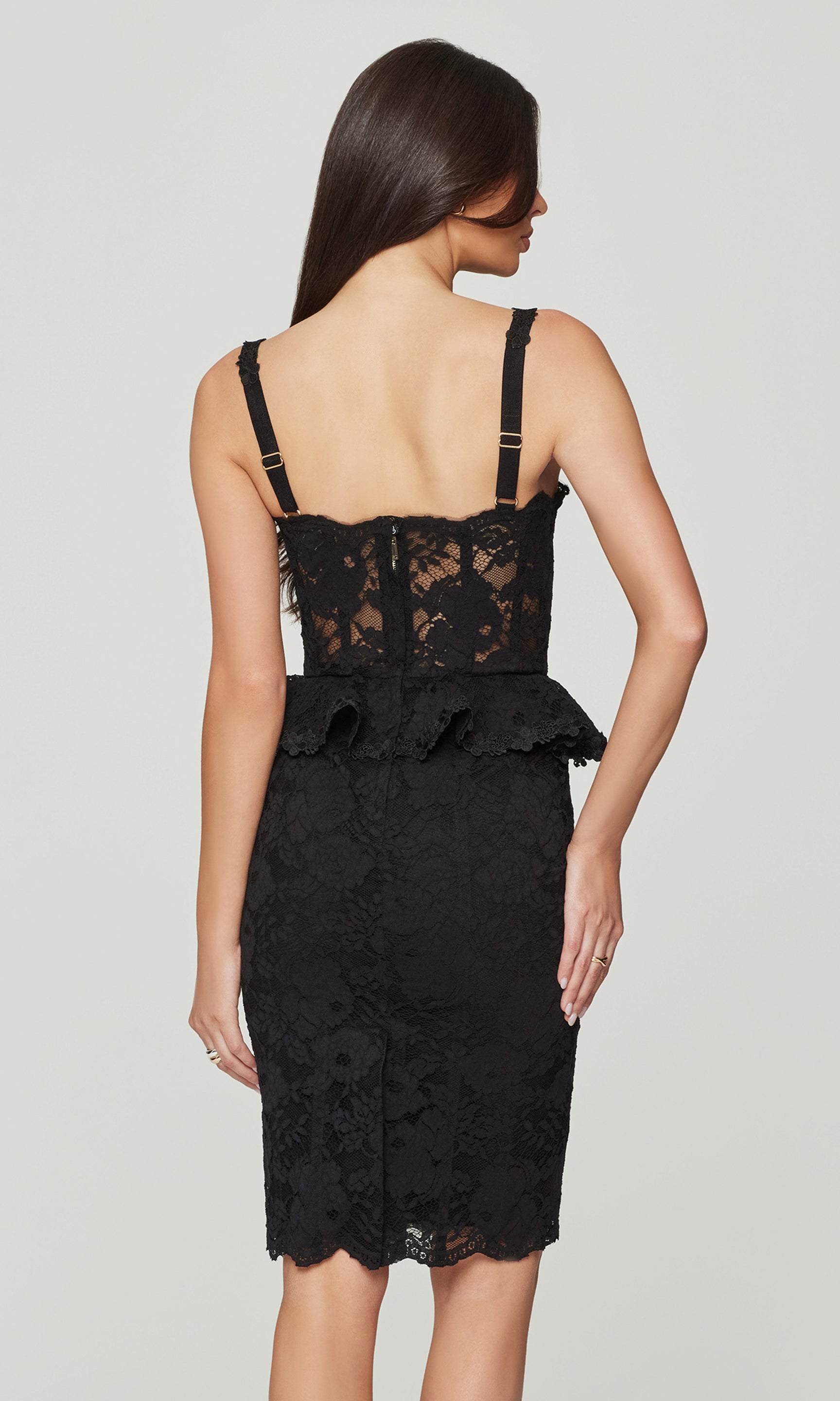 Black lace dress with a peplum waist on a plain background