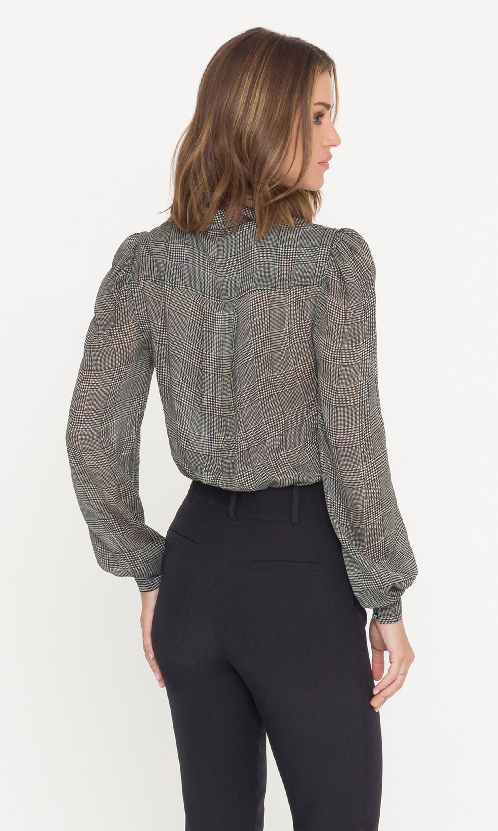 Woman wearing a plaid blouse and black pants on a white background