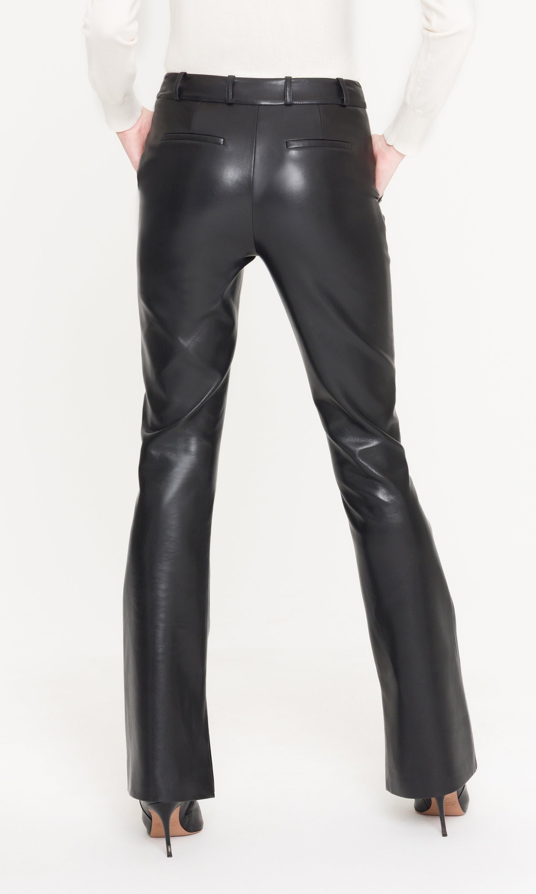 Back view of black leather pants worn by a person on a white background