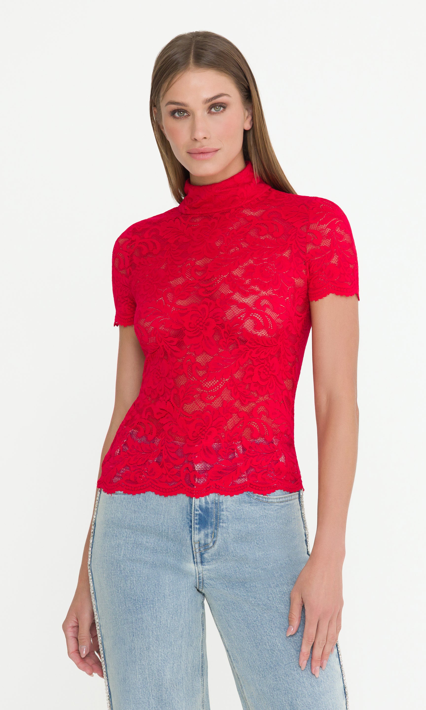 Front 3/4 view of woman wearing a red lace top and light blue jeans on a white background
