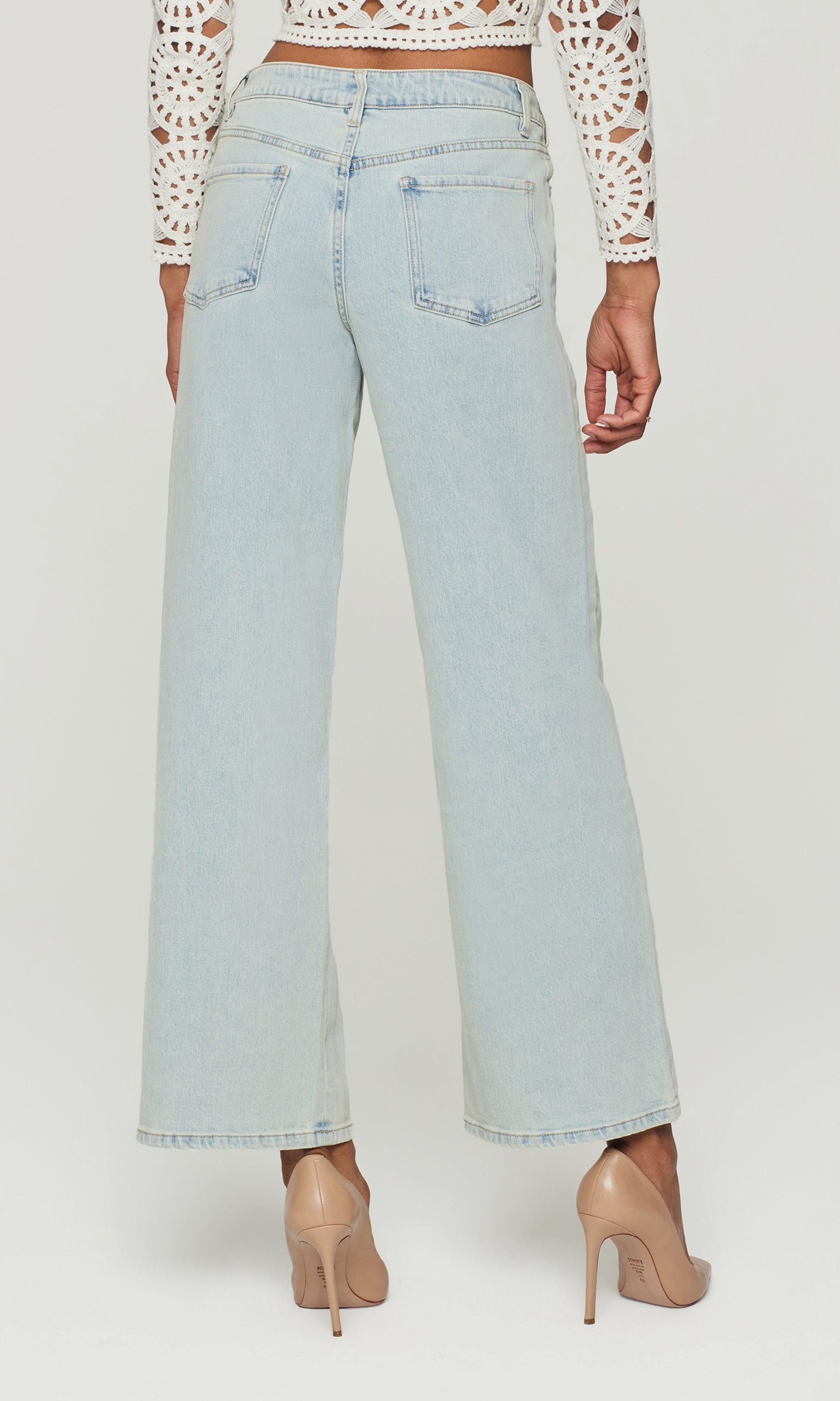 Back view of light blue jeans worn by a person on a white background
