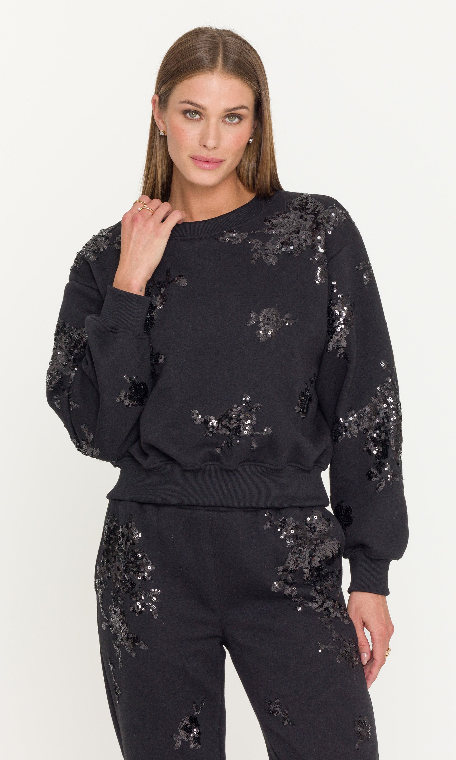 Woman wearing a black sequin sweatsuit outfit on a white background