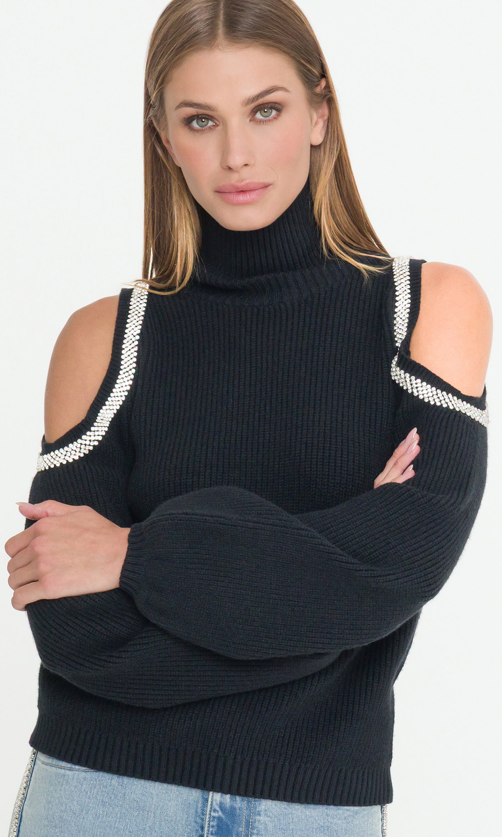 Woman wearing a black sweater with crystals shoulder embellishments on a white background