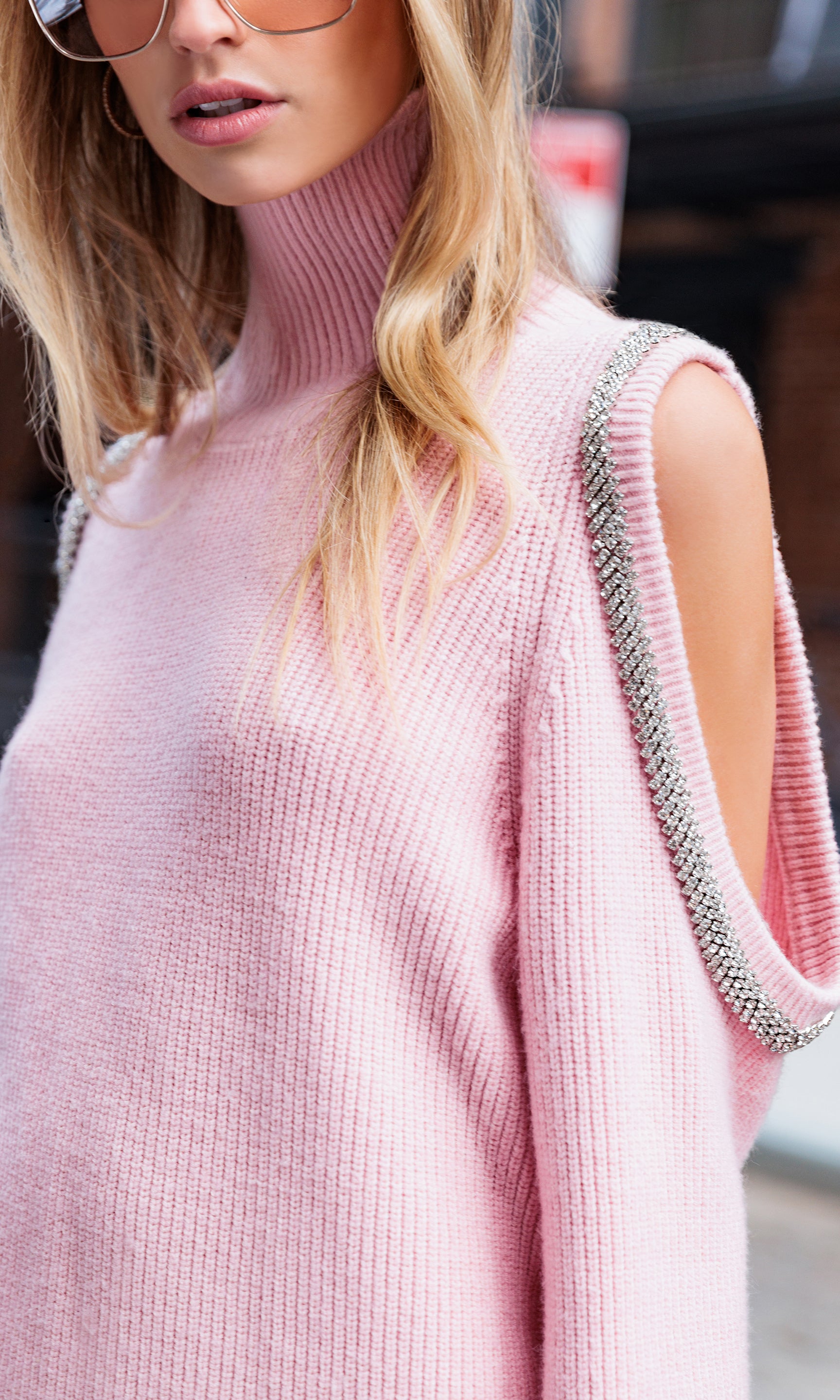 Pink shoulder cut-out sweater with embellished shoulders worn by a person.