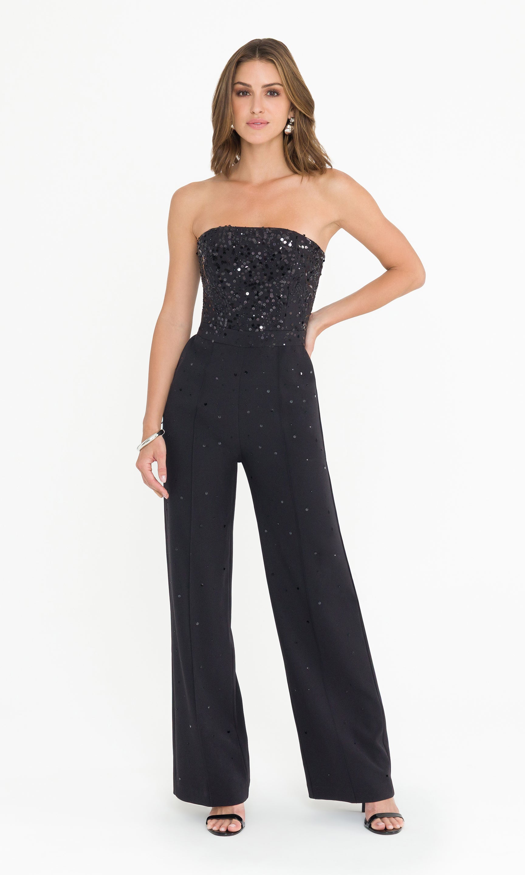 Woman wearing a black strapless sequin jumpsuit on a white background