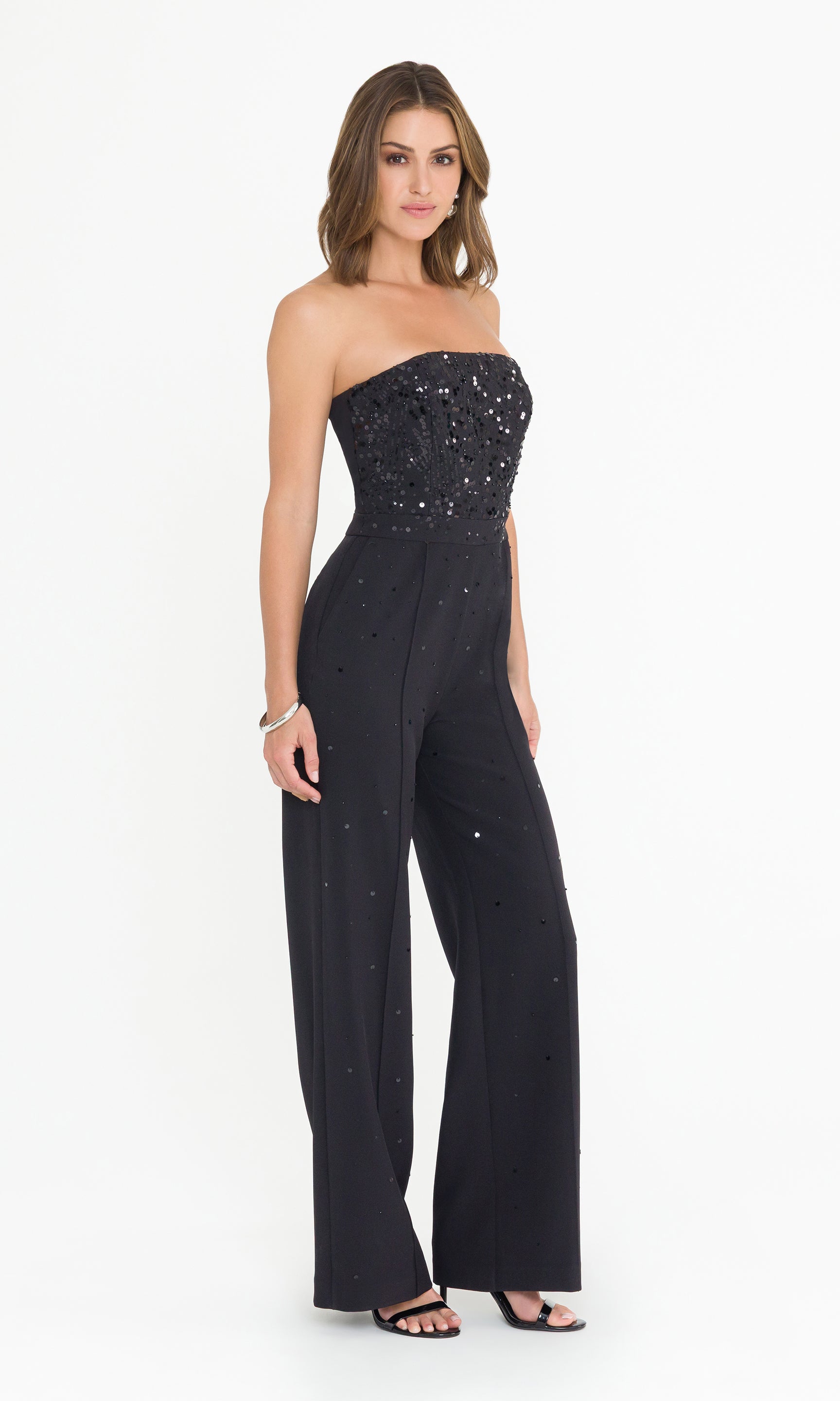 Side view full body image of model wearing a black strapless jumpsuit on a white background