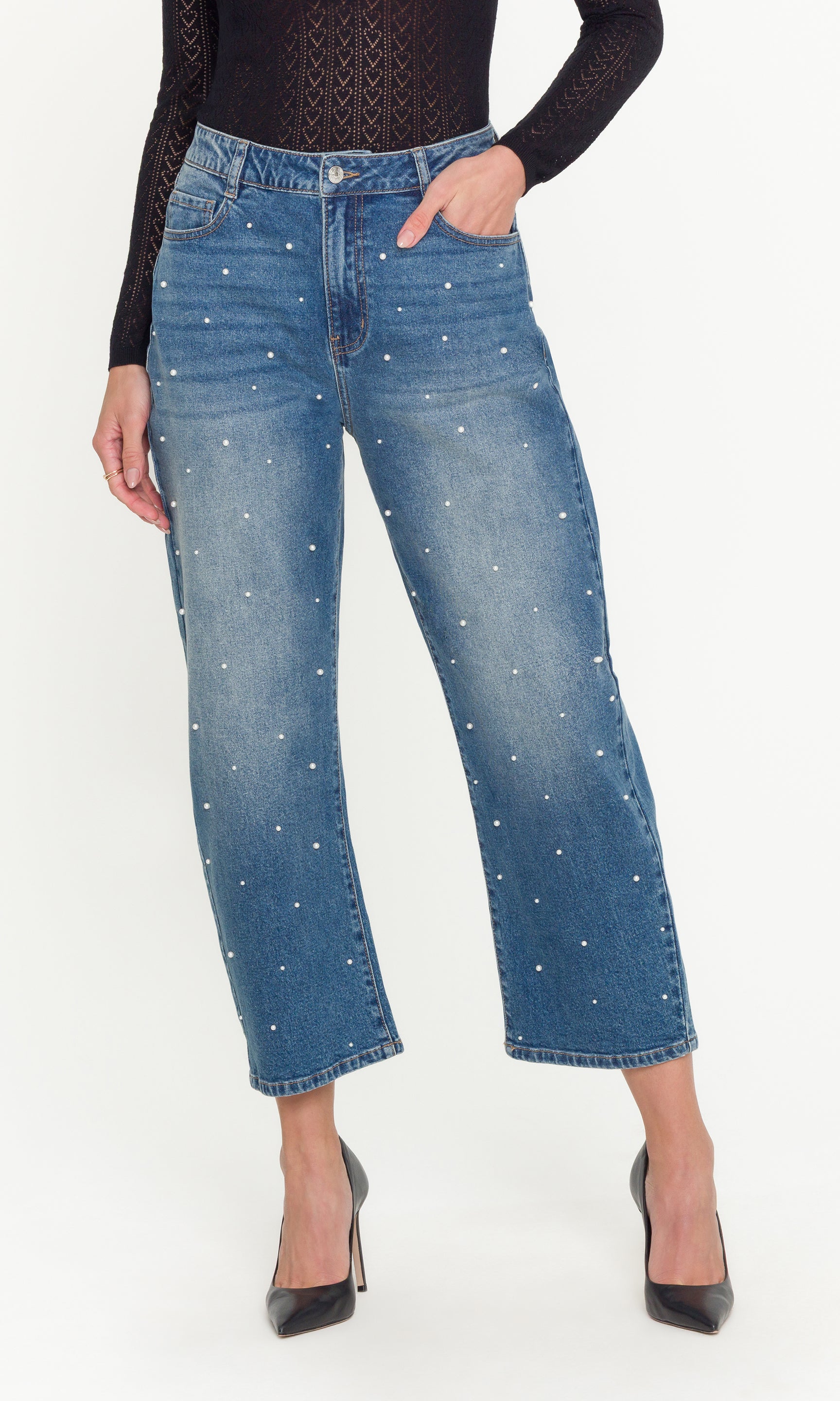 Blue jeans with pearl embellishments worn by a person on a white background